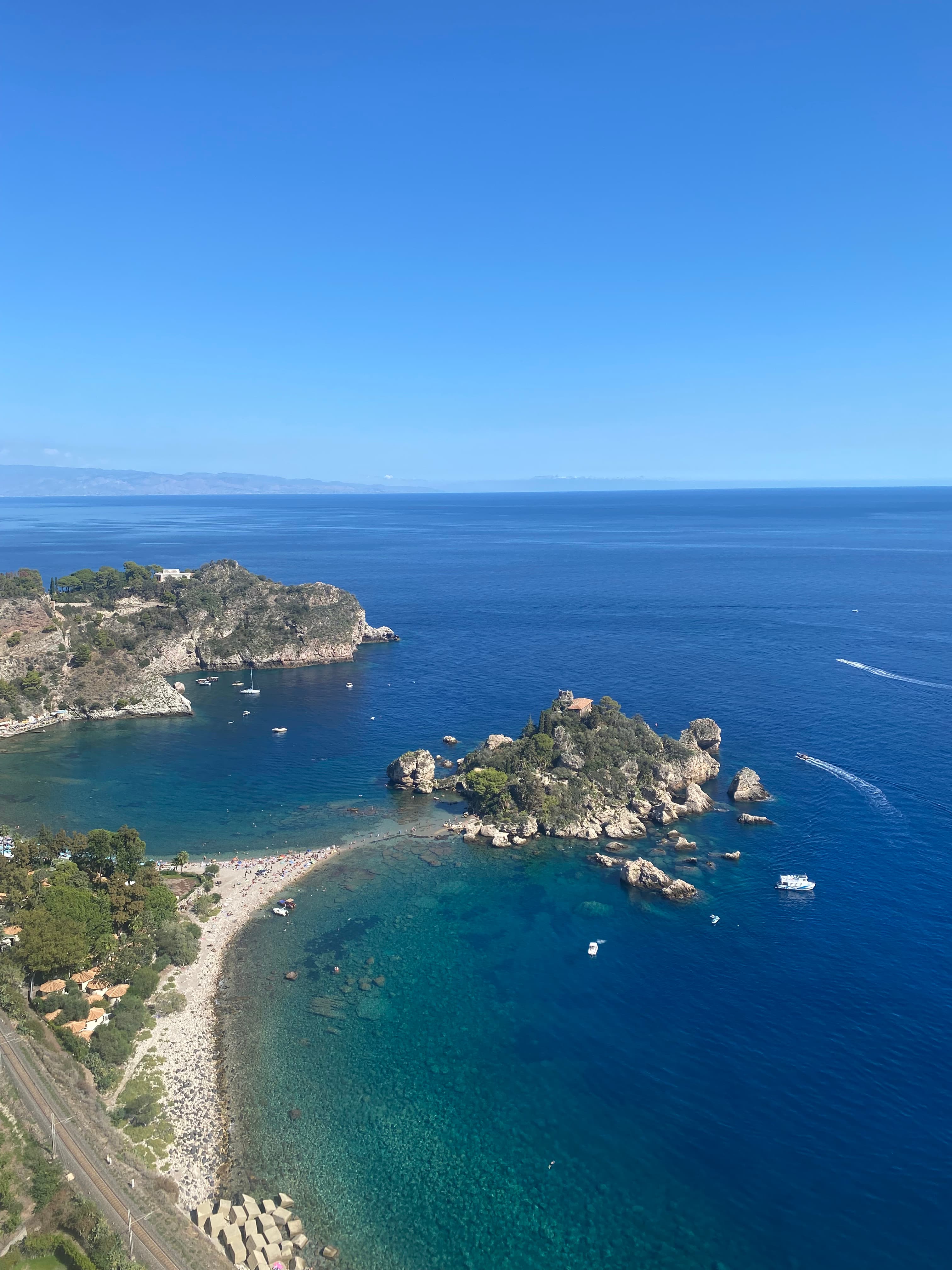 Aerial view of twin bays and a stretch of beach leading to a rock formation on a clear day