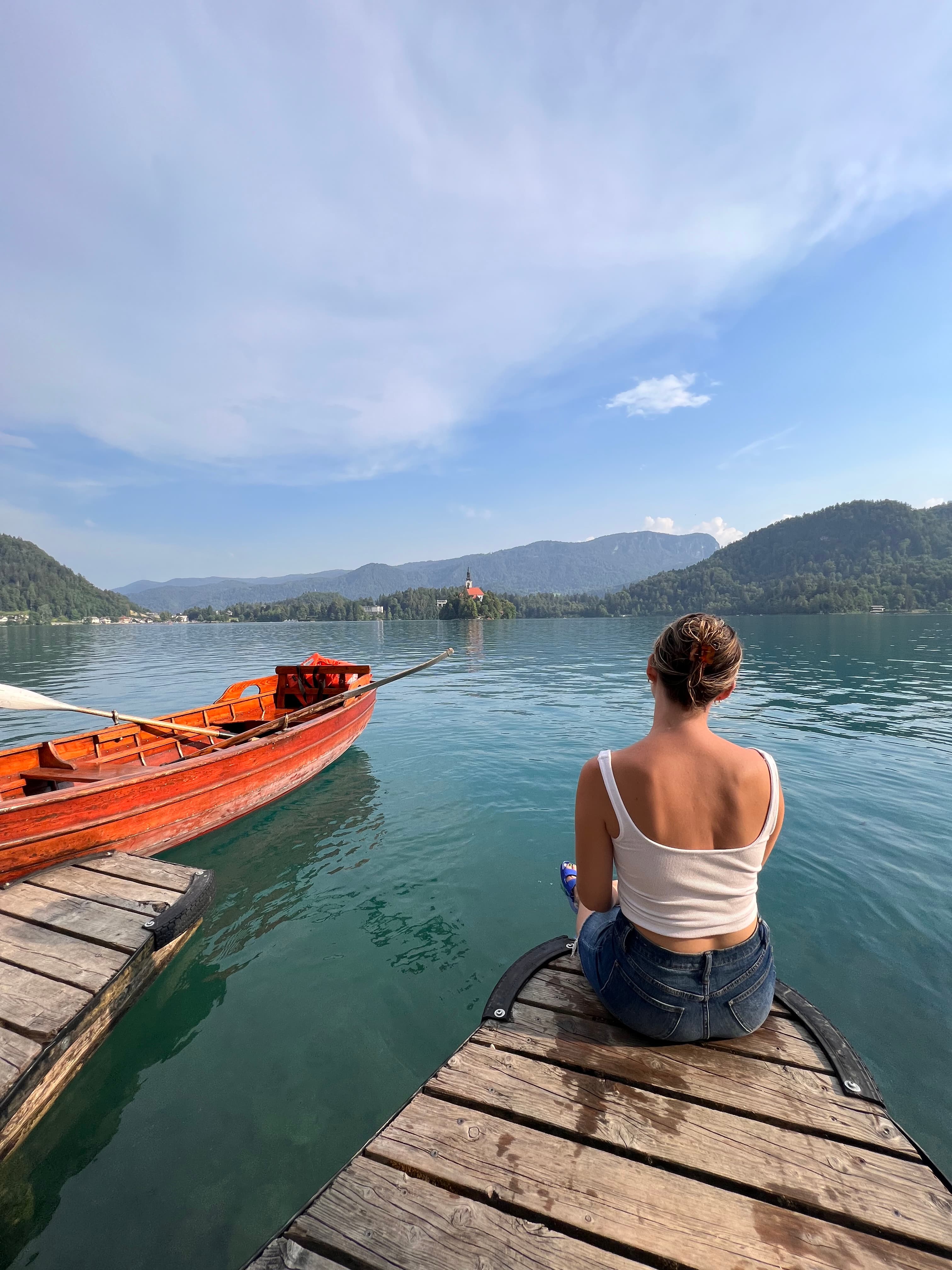 Picture of Courtney on a dock at Lake Bled with boats in the water.