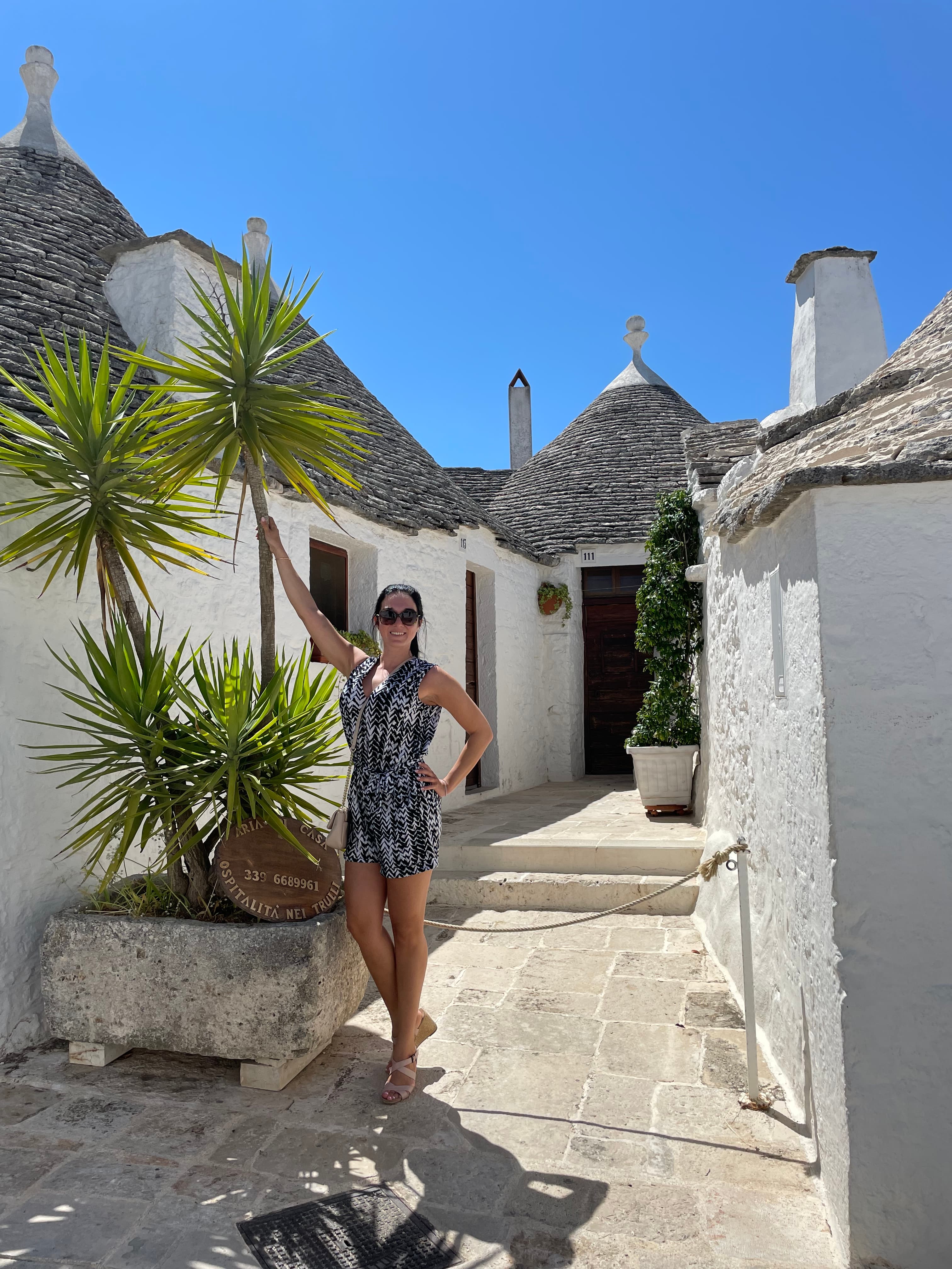 Travel Advisor posing outside of white buildings with palm trees.