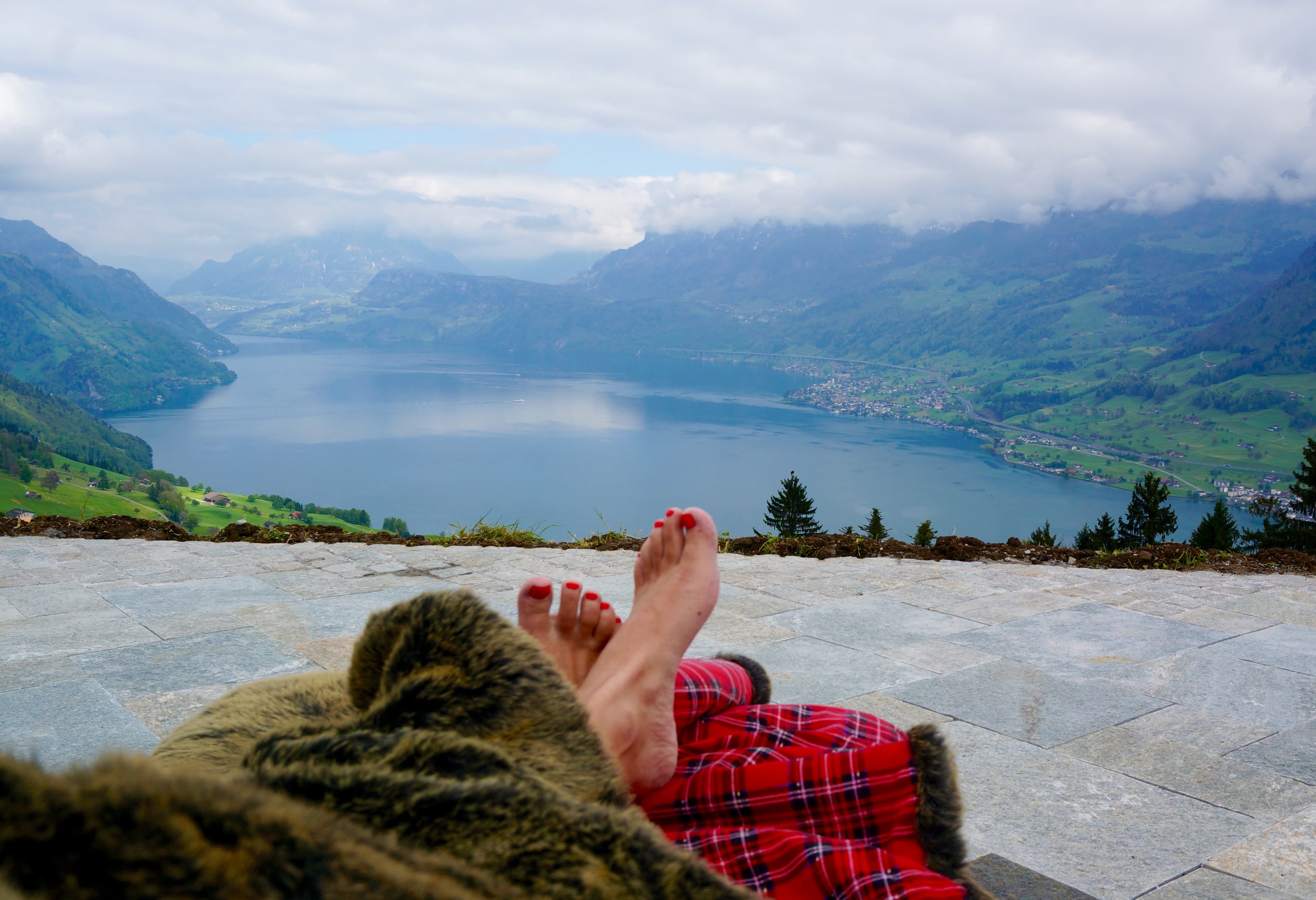 Kara lounging at Hotel Villa Honegg with a view of a lake and cloudy mountains in the distance