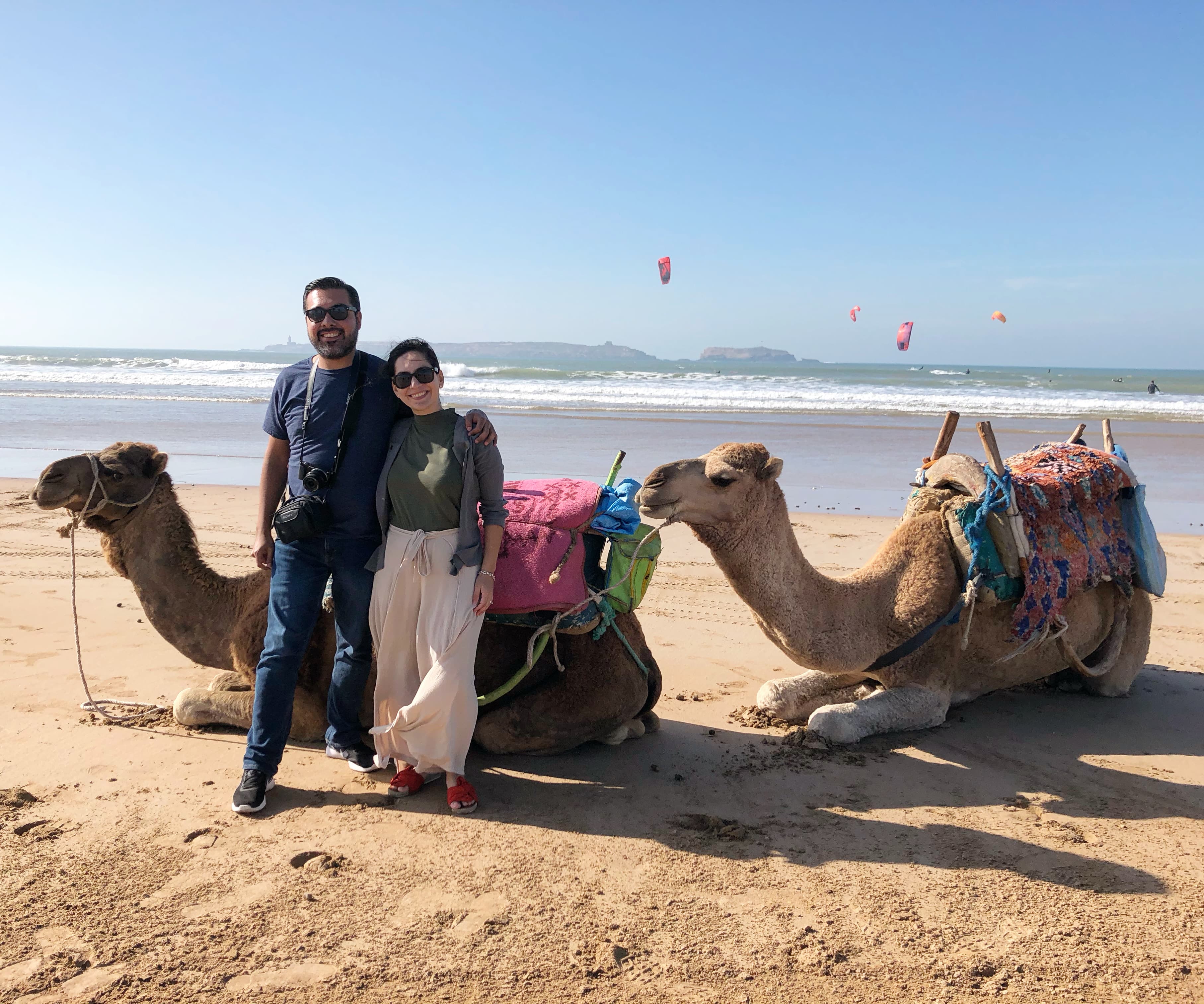 Couple posing with two camels on the beach