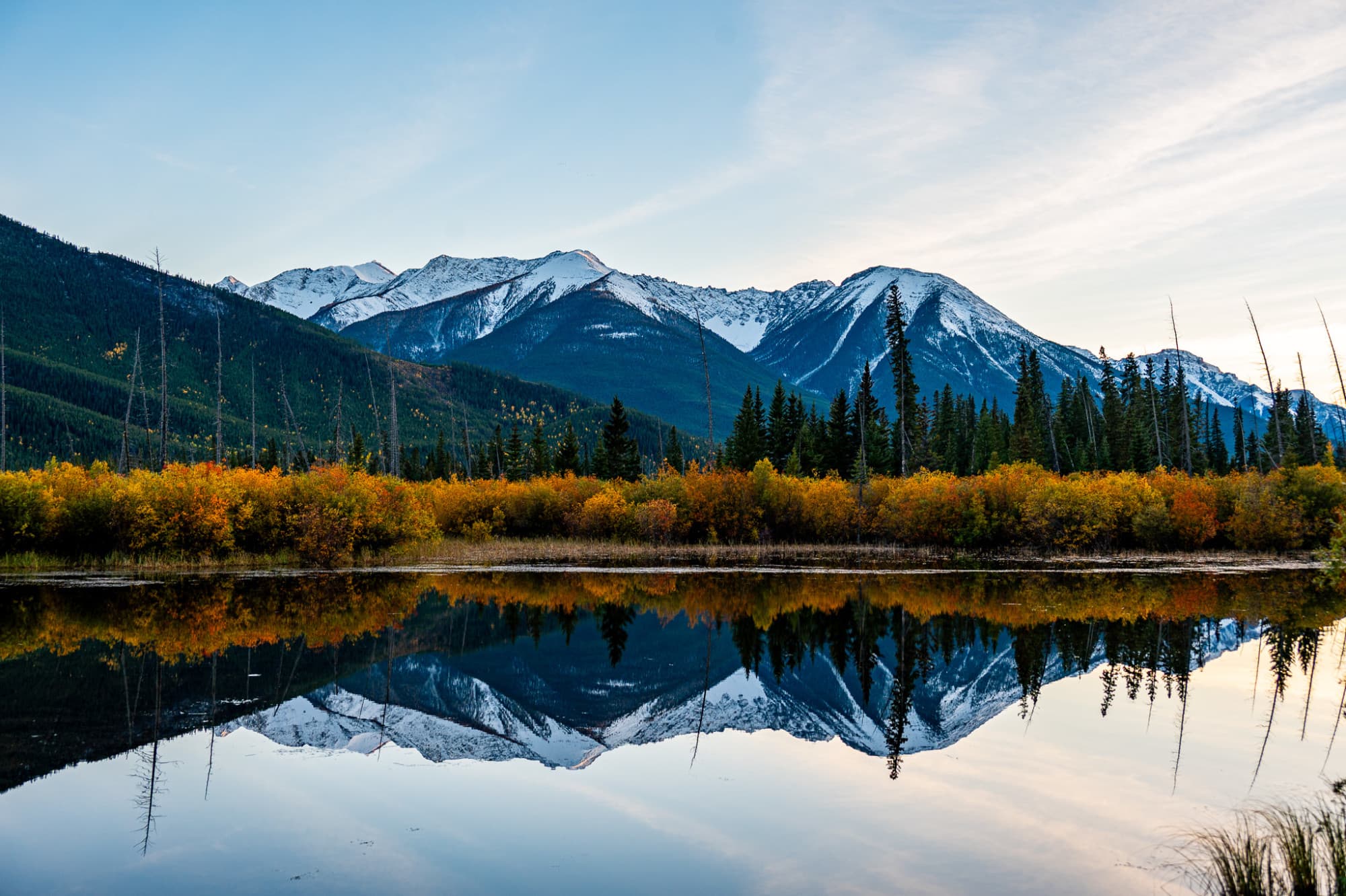 A clear lake with reflection of mountains and trees in it.
