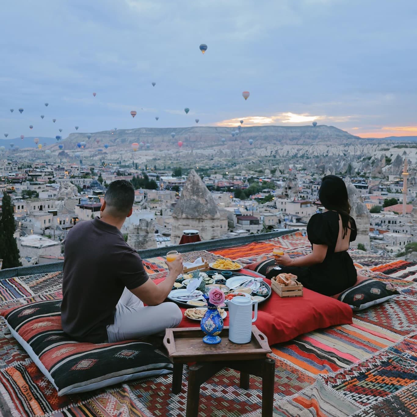 A man and woman dining on a roof top overlooking the city.