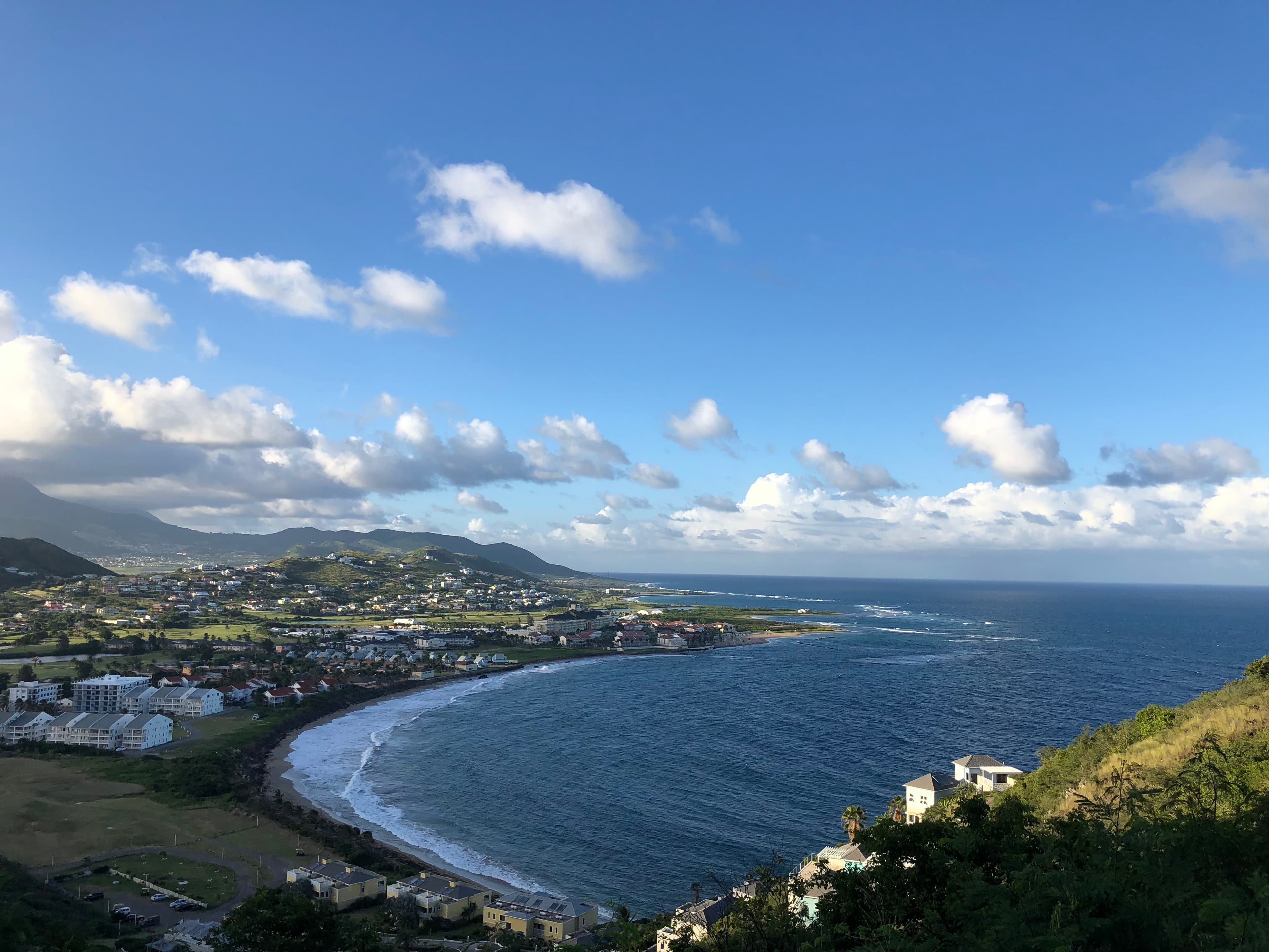 An aerial view of St Kitts And Nevis Frigate Bay Of The South highlighting blue water and a town built into a coastal mountain range
