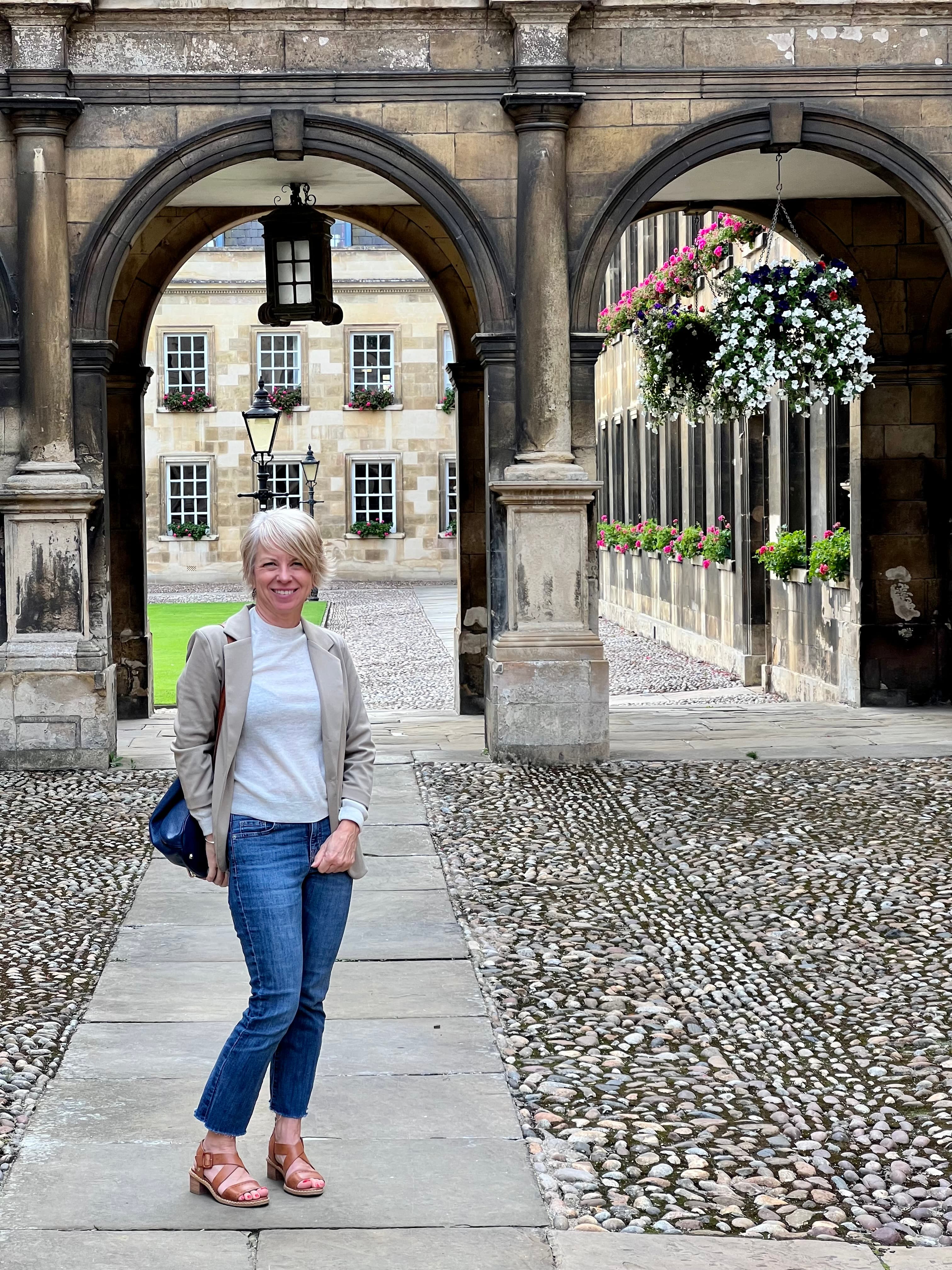 A woman standing in front of the building wearing blue jeans and a white shirt