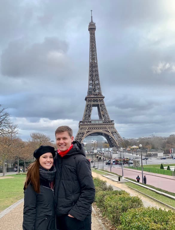 Picture of Amber and spouse wearing jackets in front of the Eiffel Tower