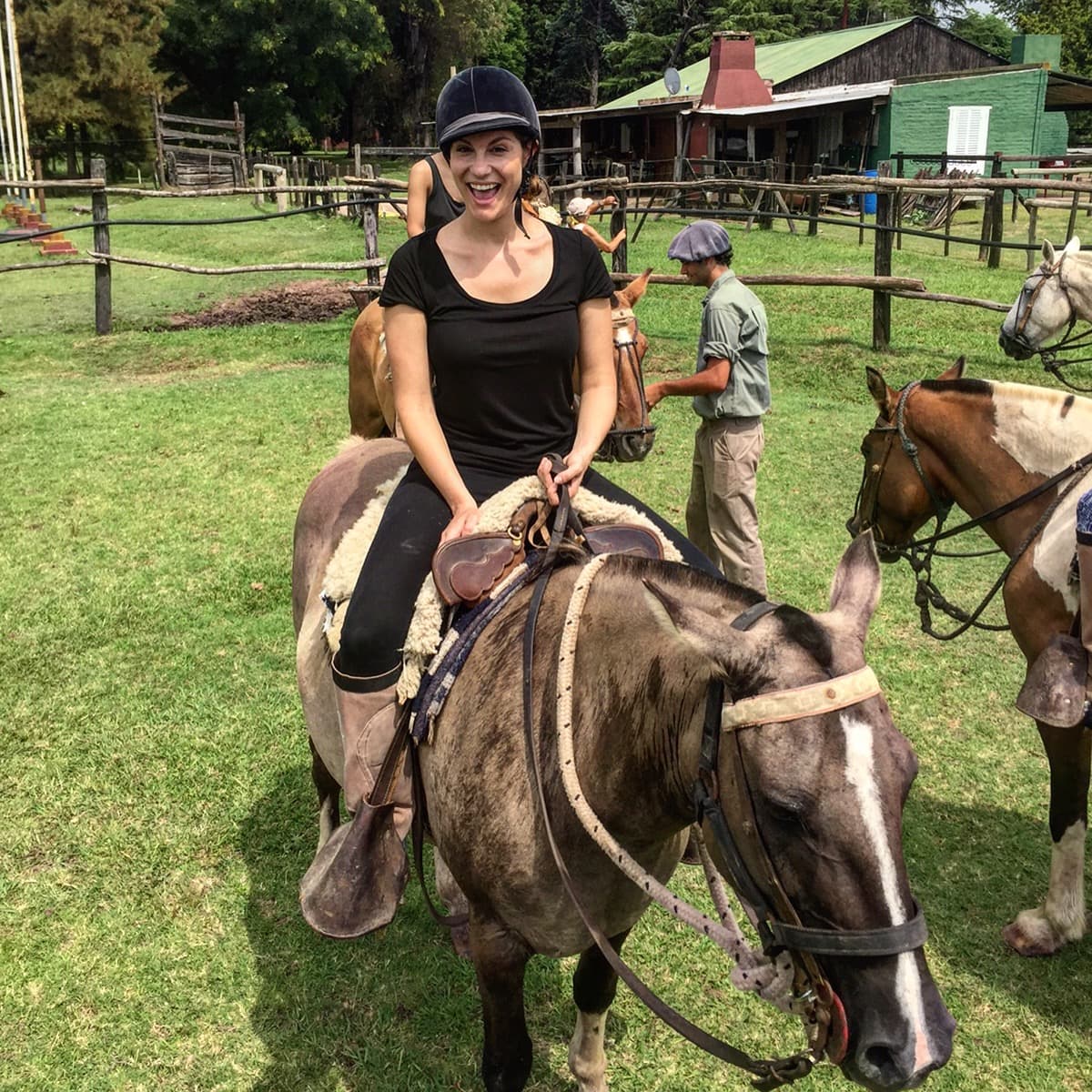 Woman in a black top rides a brown horse.