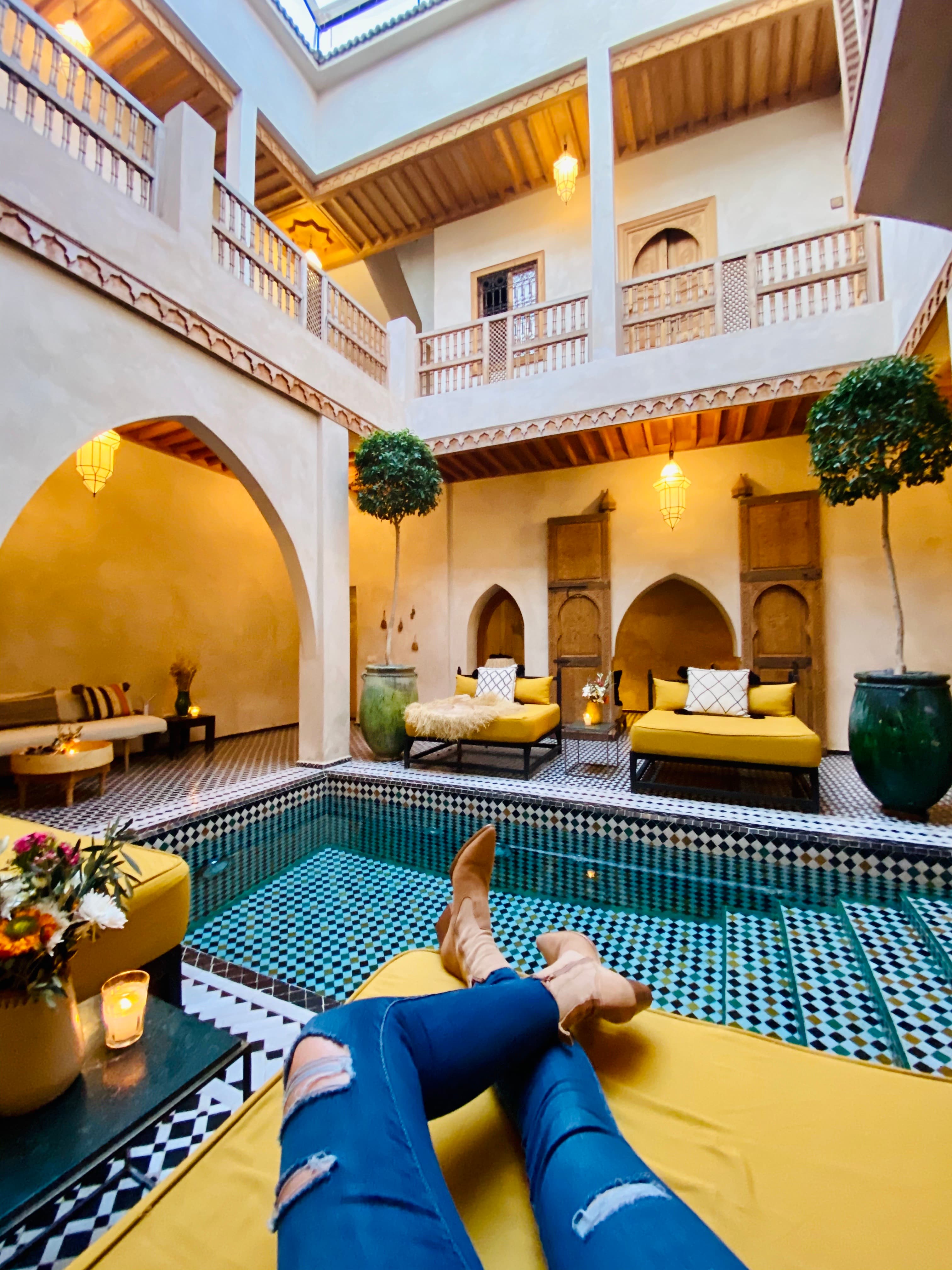 A person chilling in front of an indoor tiled pool.