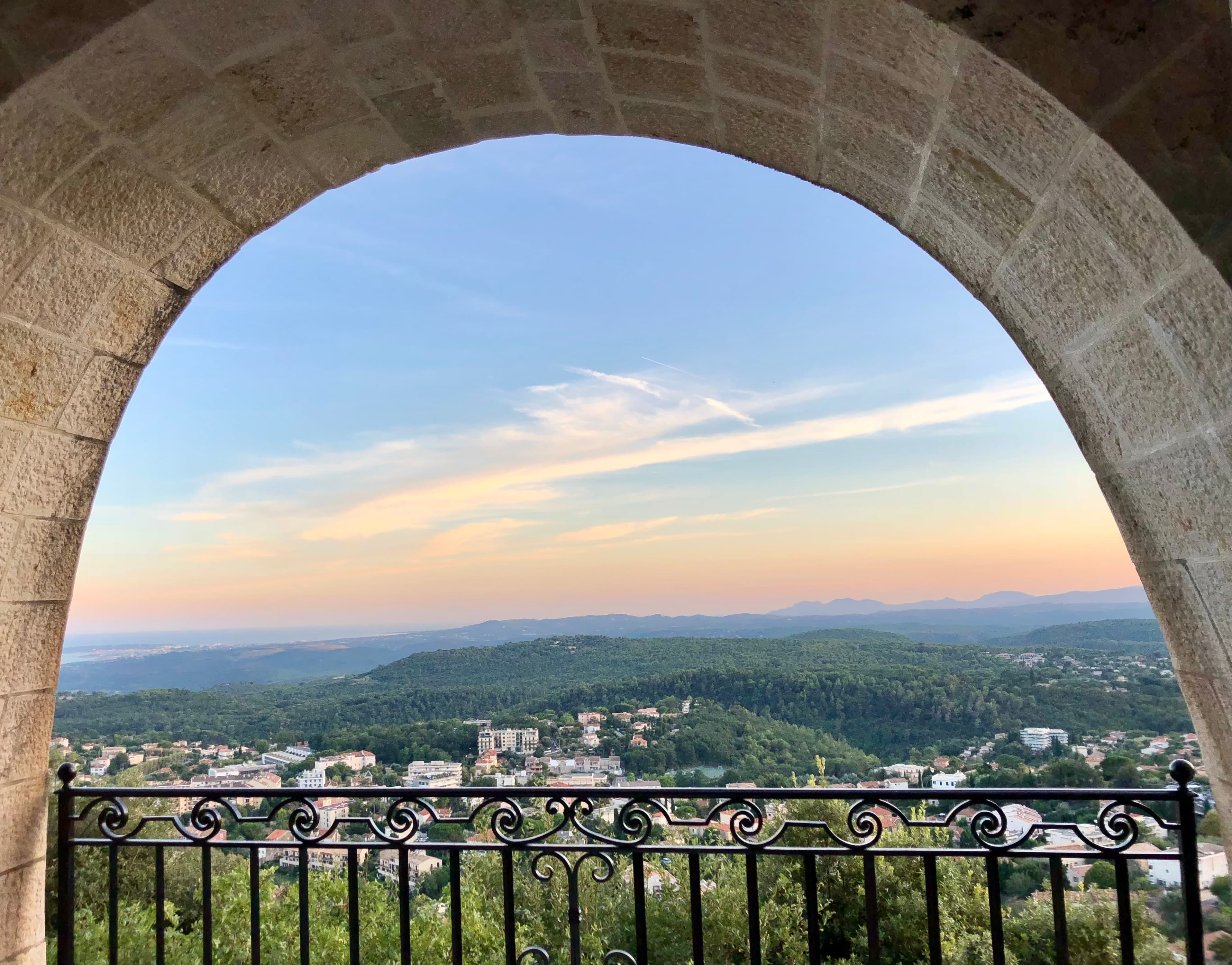 A beautiful view of a city at sunset from an arched balcony