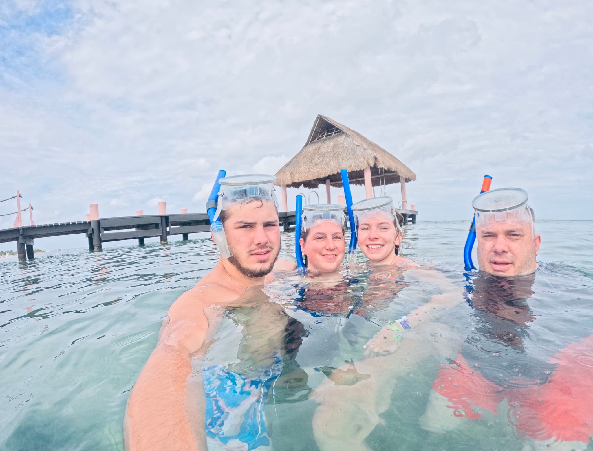 Four people with snorkeling equipment, taking a selfie in the sea