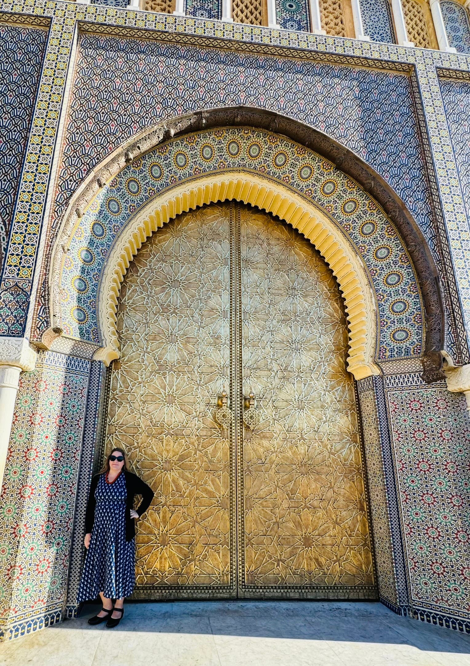 Karyn standing in front of the Royal Palace with golden doors and beautiful arch way.
