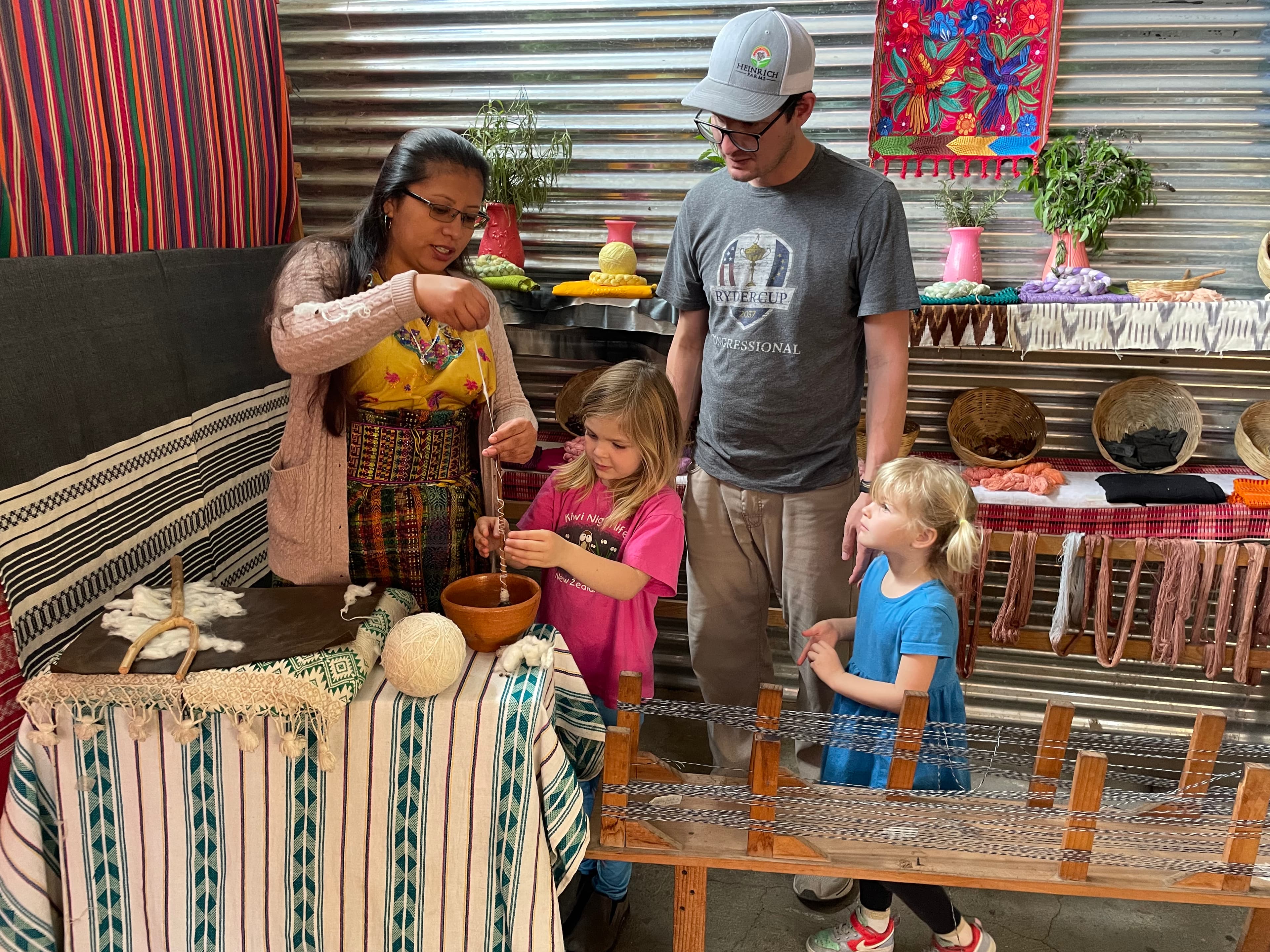 A family in an artisan shop observing a craft process involving string