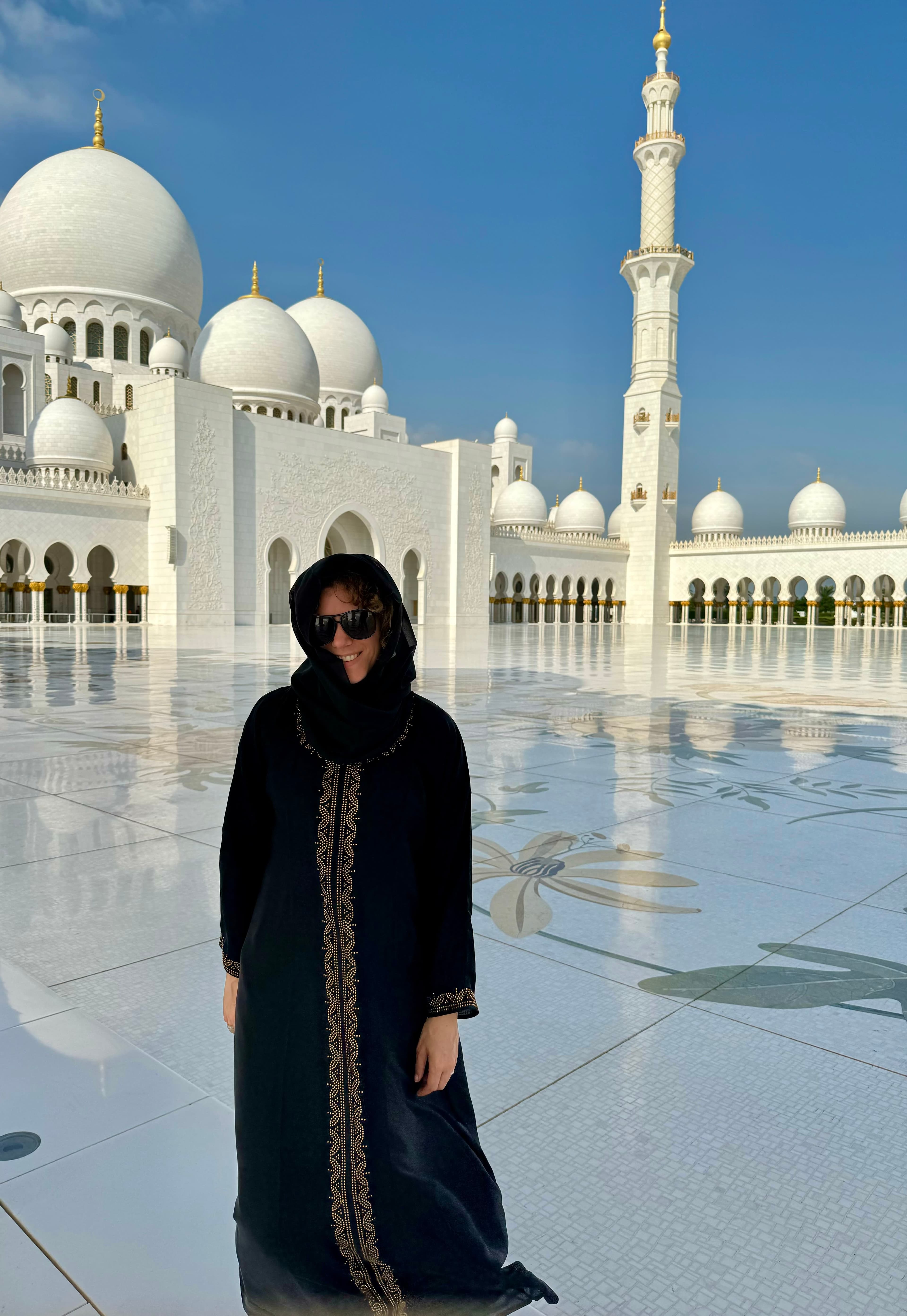 Travel advisor Alexandra standing in front a white mosque in Abu Dhabi dressed in black clothes and headscarf