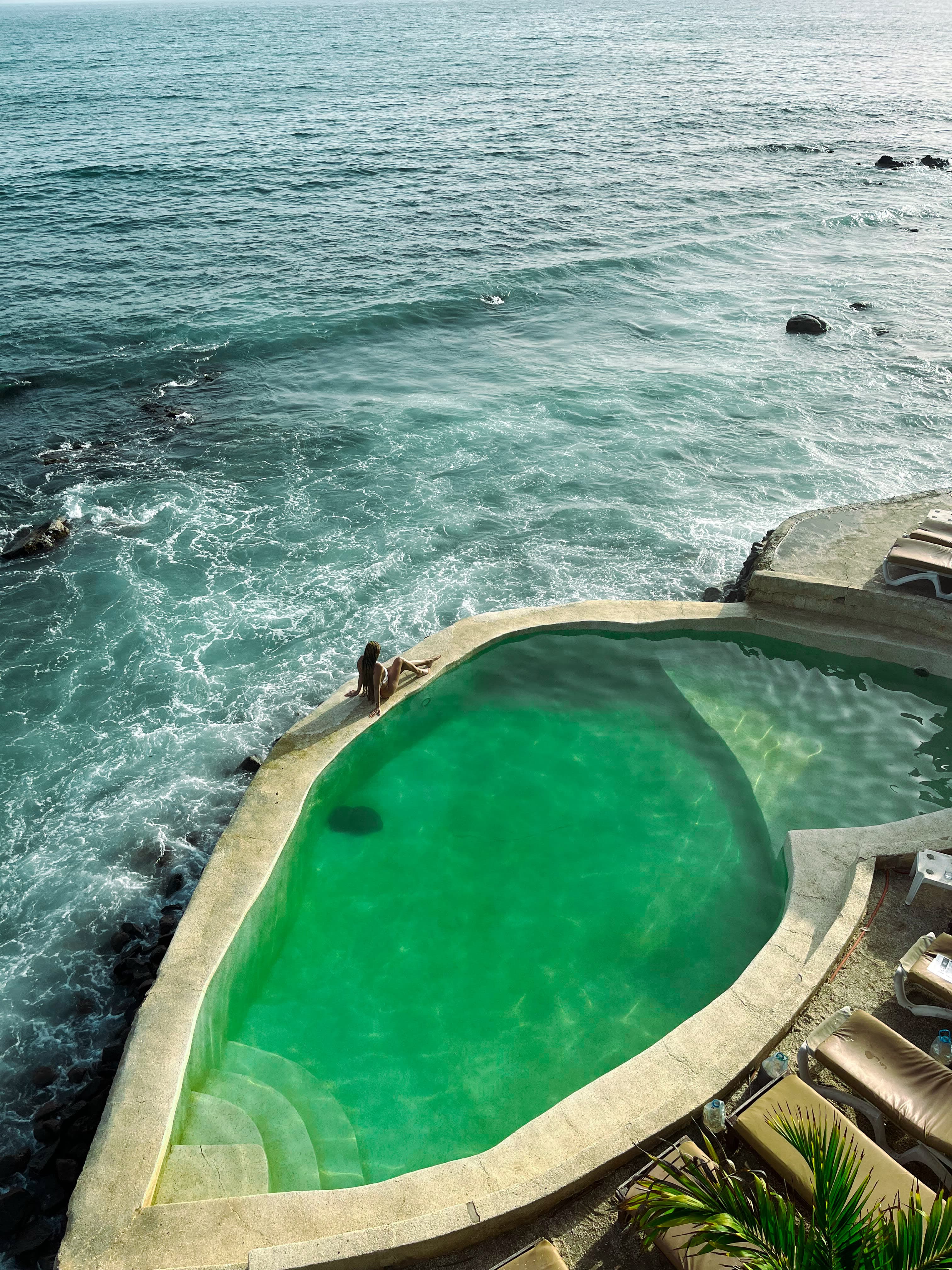 Sitting on the edge of the pool by the sea