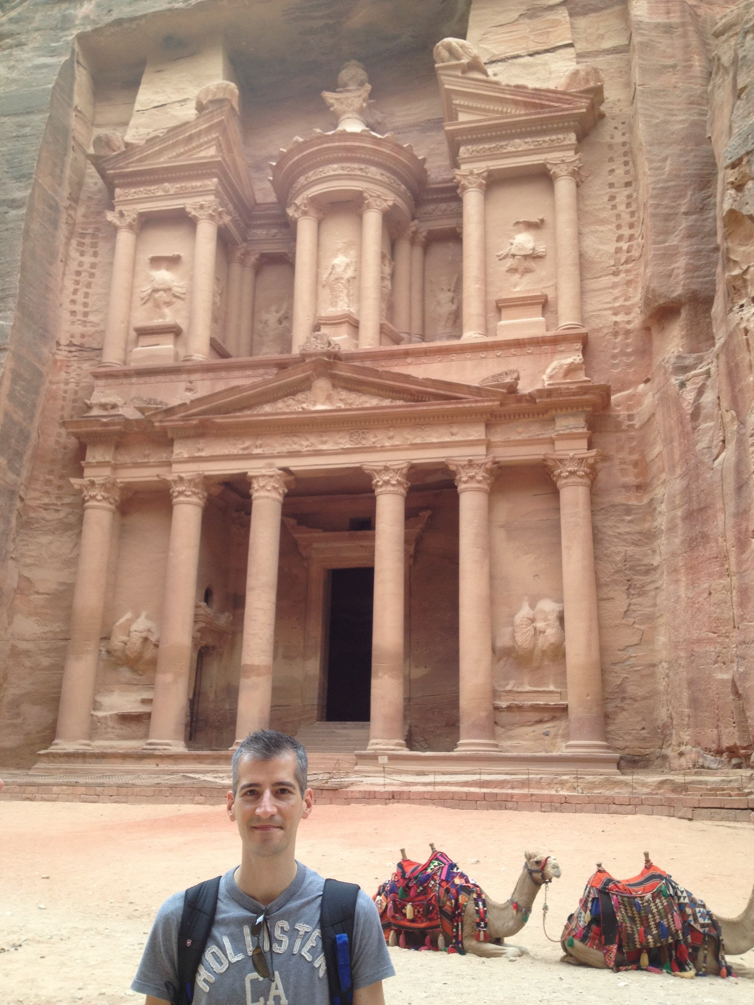 Advisor standing in desert setting with camels in the background and an ancient ruins in the distance.