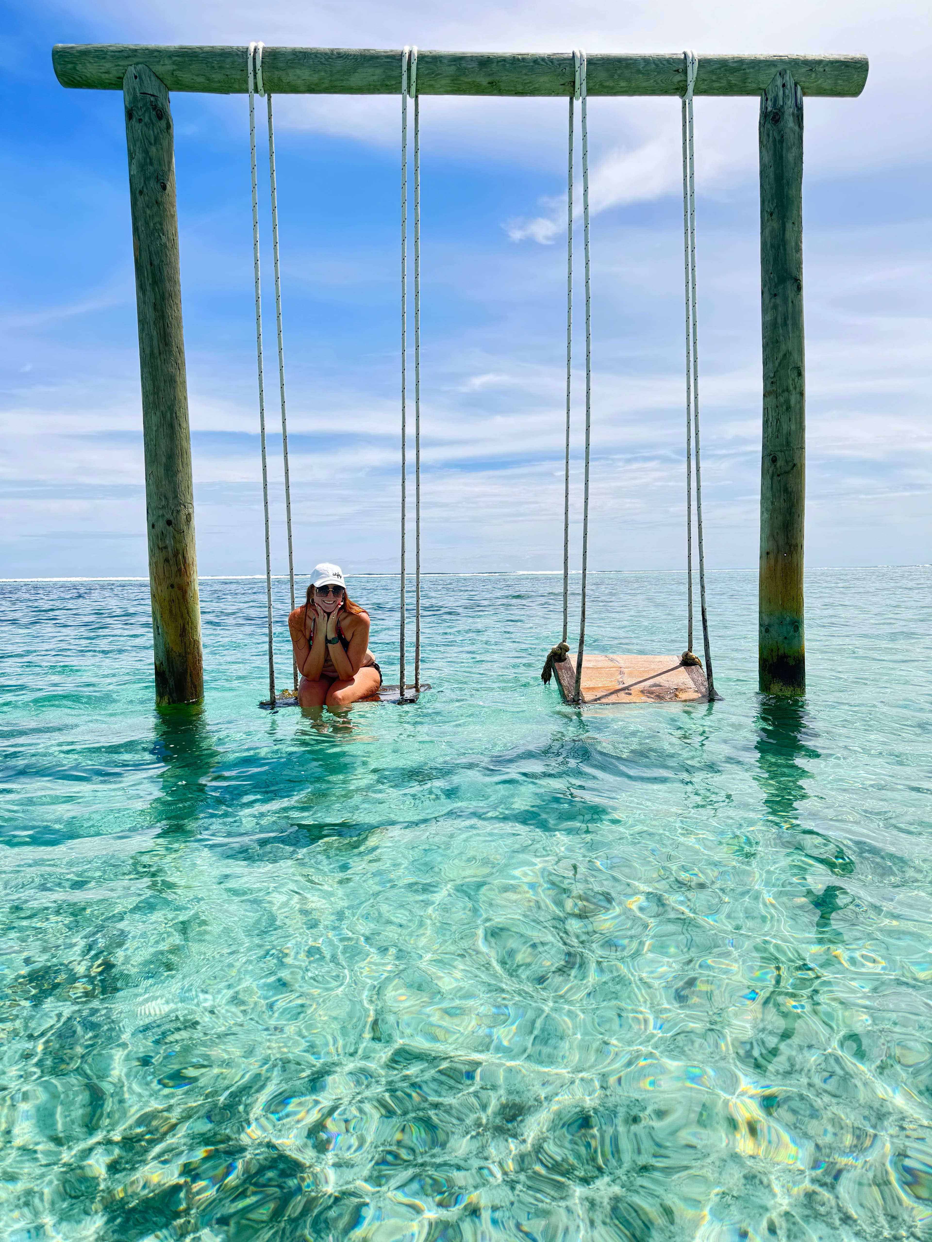 Advisor on a wooden swing set in clear and shallow ocean water on a sunny day