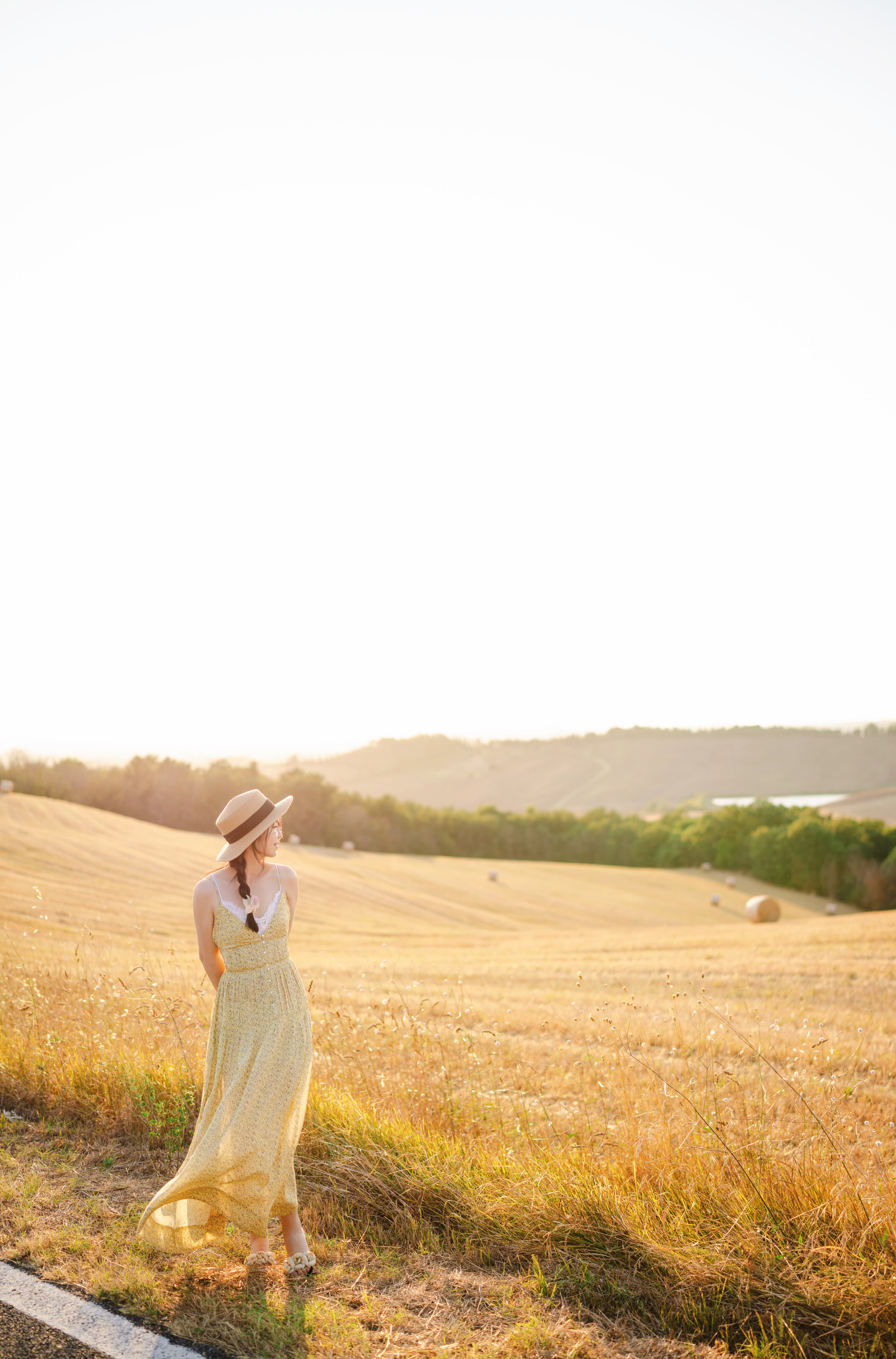 Advisor in a dress posing by a large grassy hill area the the sunlight