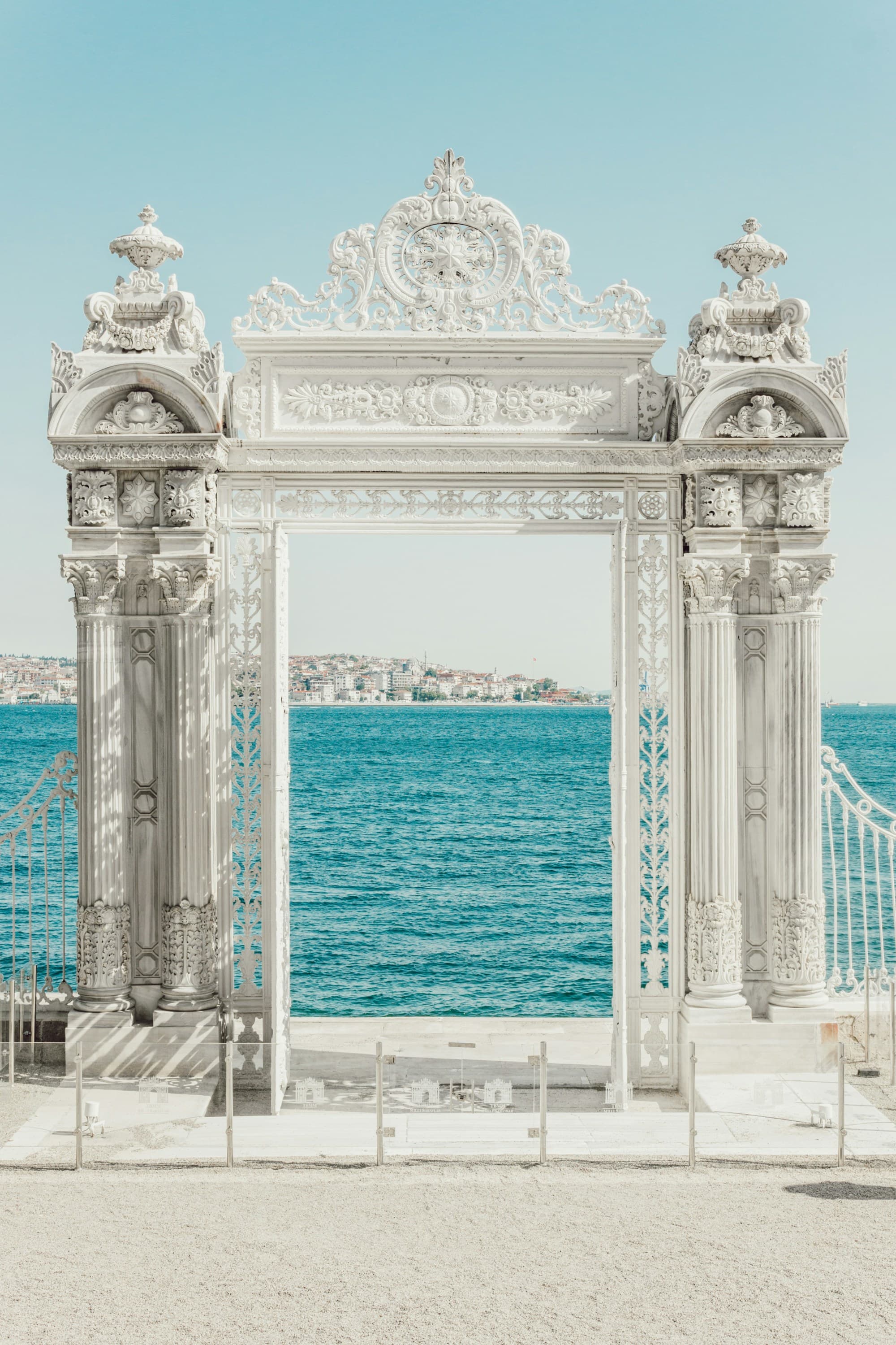 An ornate gate opens to a serene view of the sea and distant land.