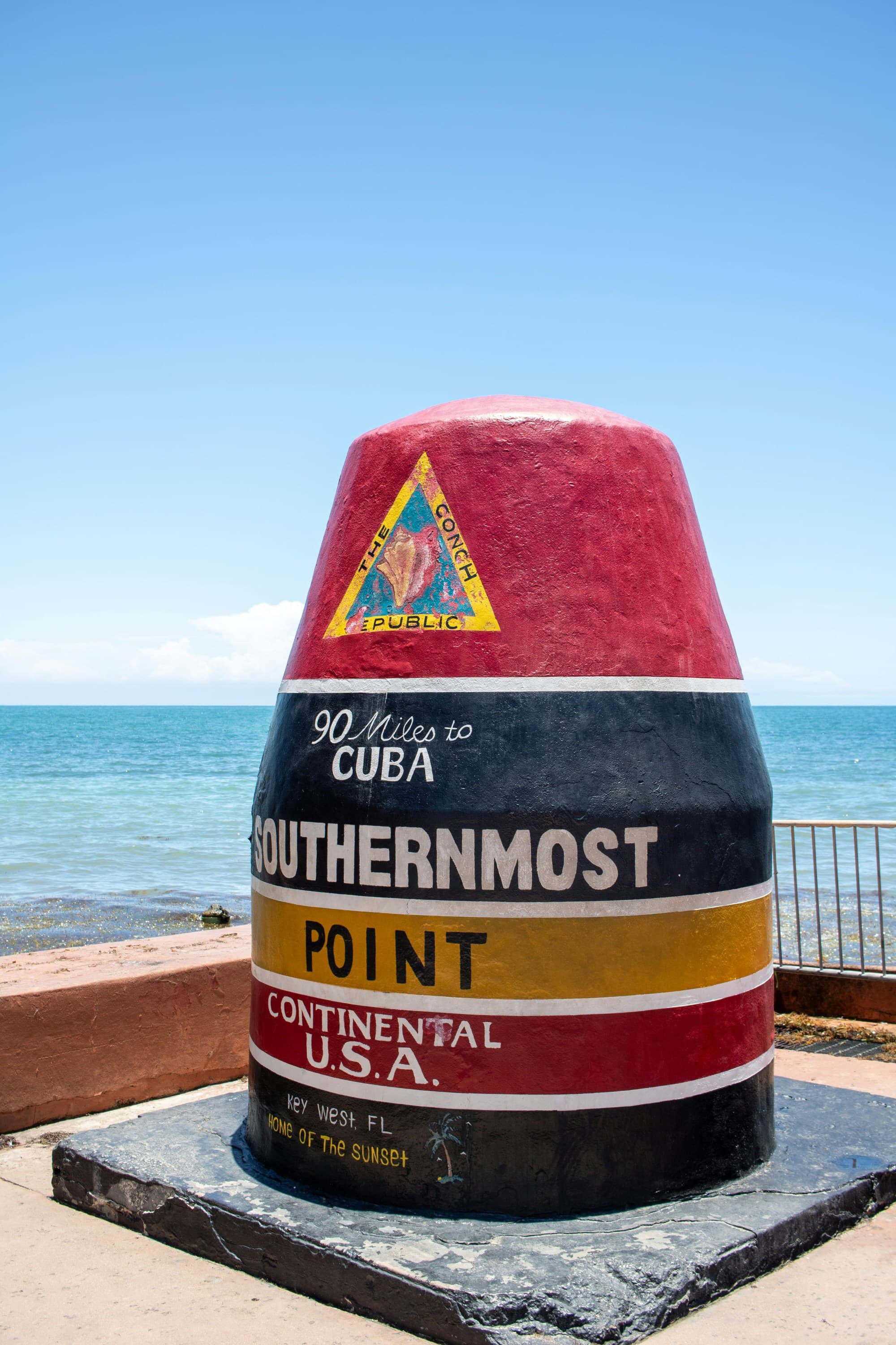 A colorful landmark next to a body of water reading "Southernmost Point, Continental USA"