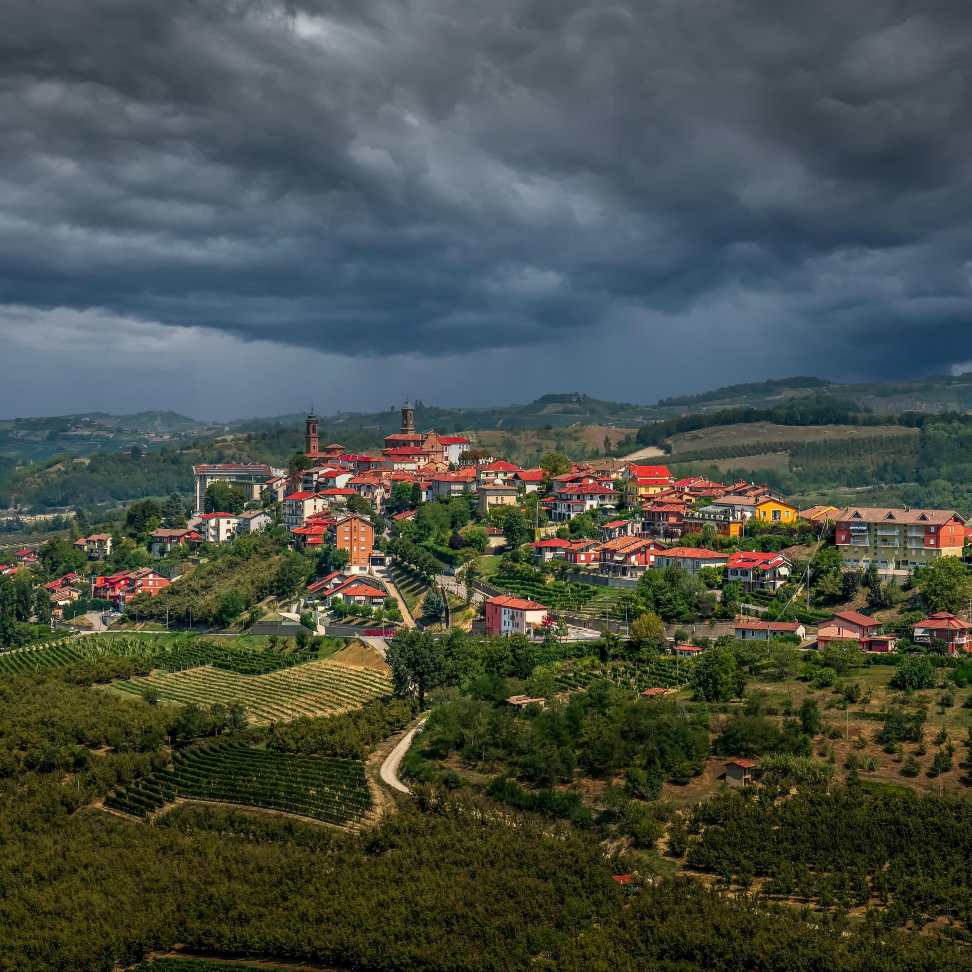 A picturesque hilltop village under a dramatic cloudy sky.