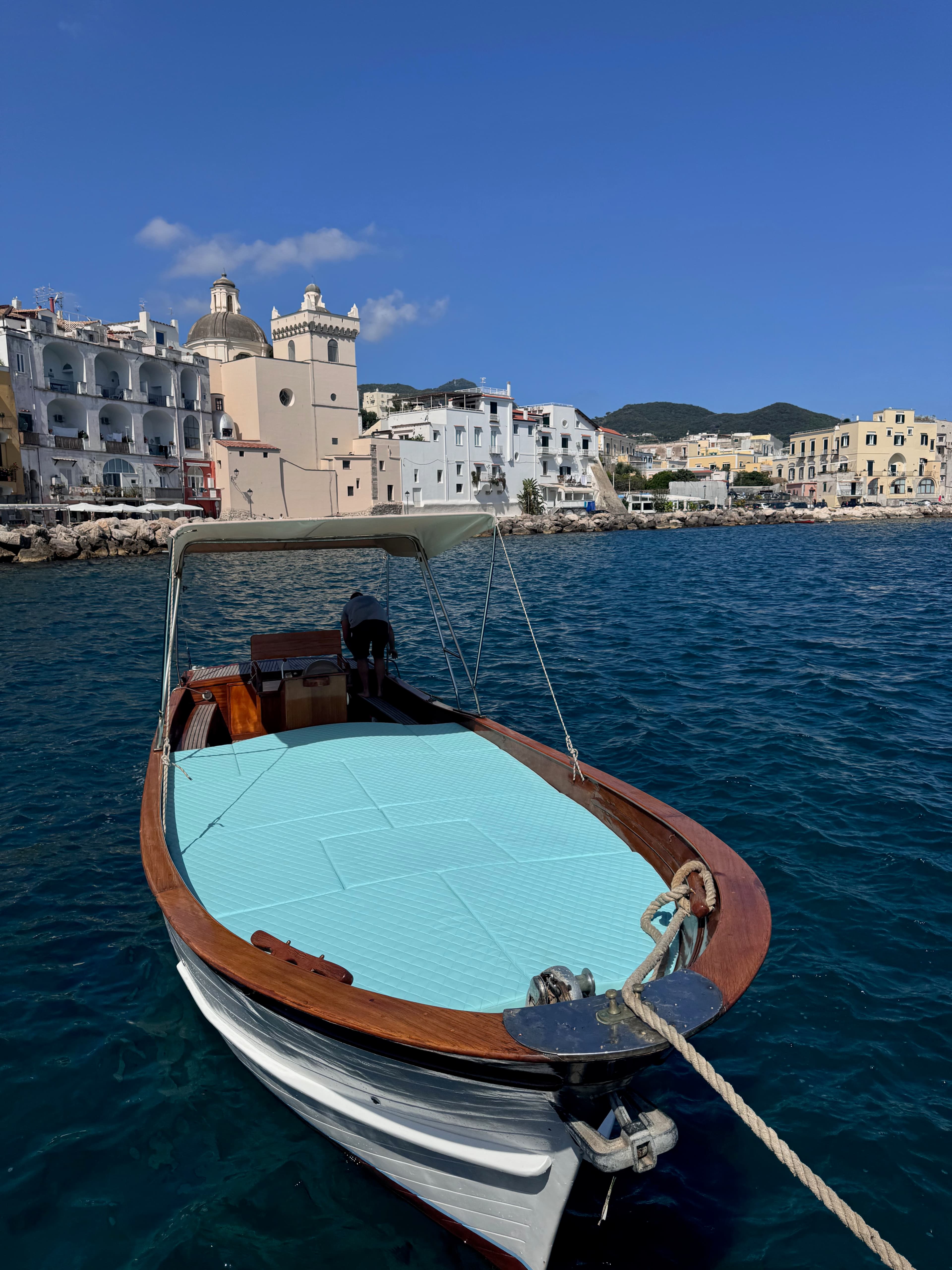 A small boat docked in a body of water with buildings on land in the distance