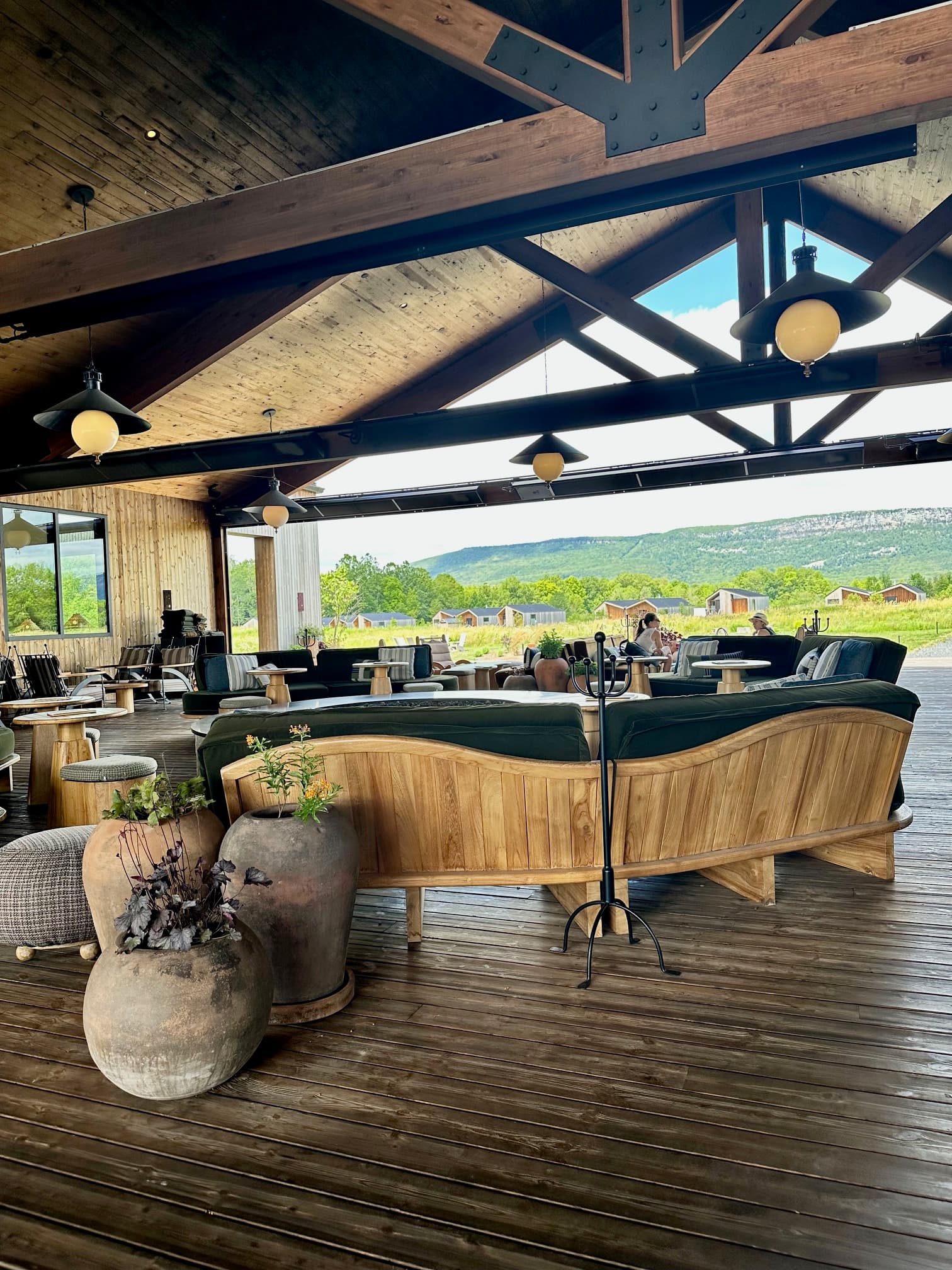 An open-air cabin space decorated with cement plant pots and wooden furniture