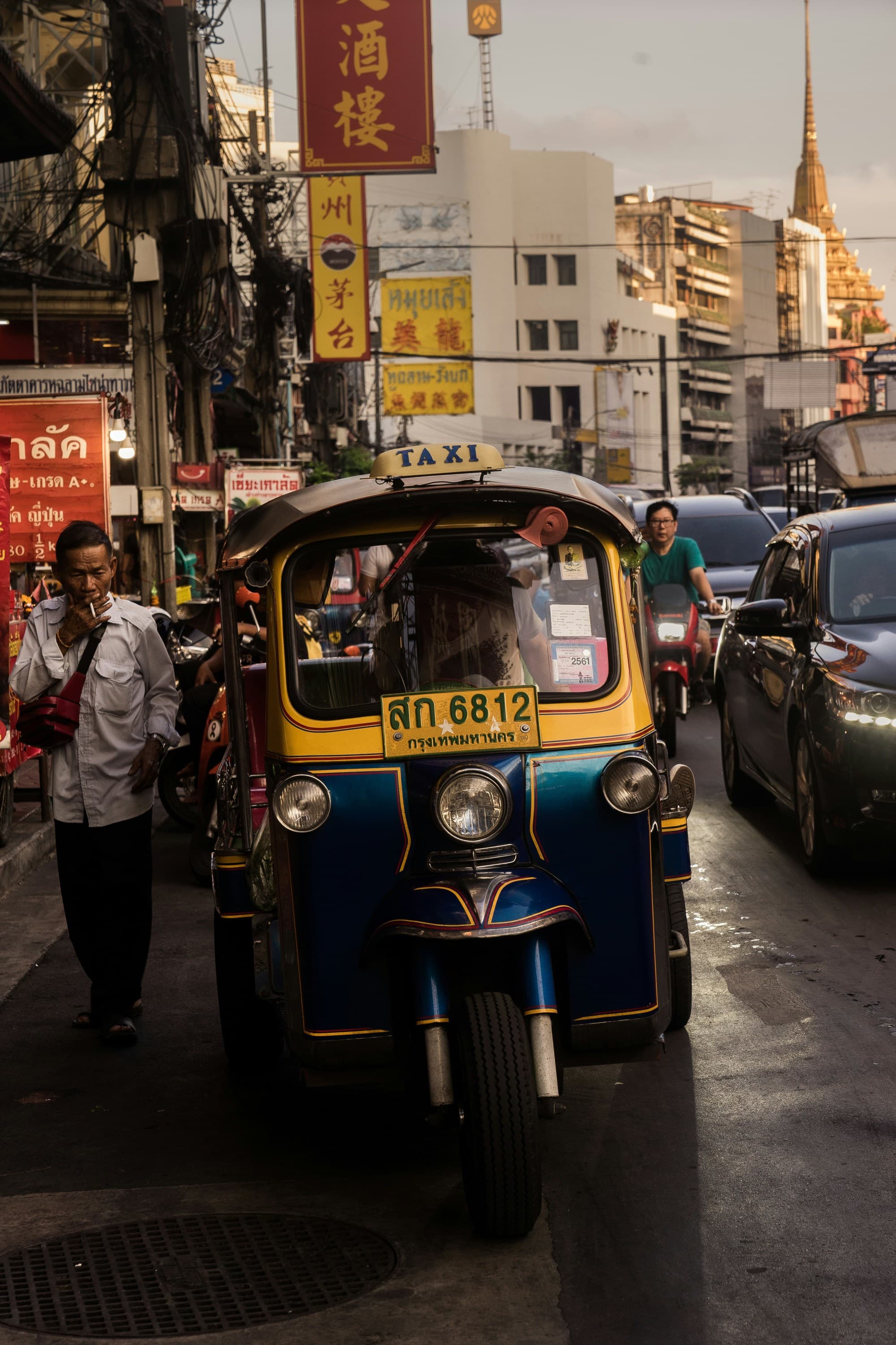 Taxi in traffic on a bustling city street at dusk.