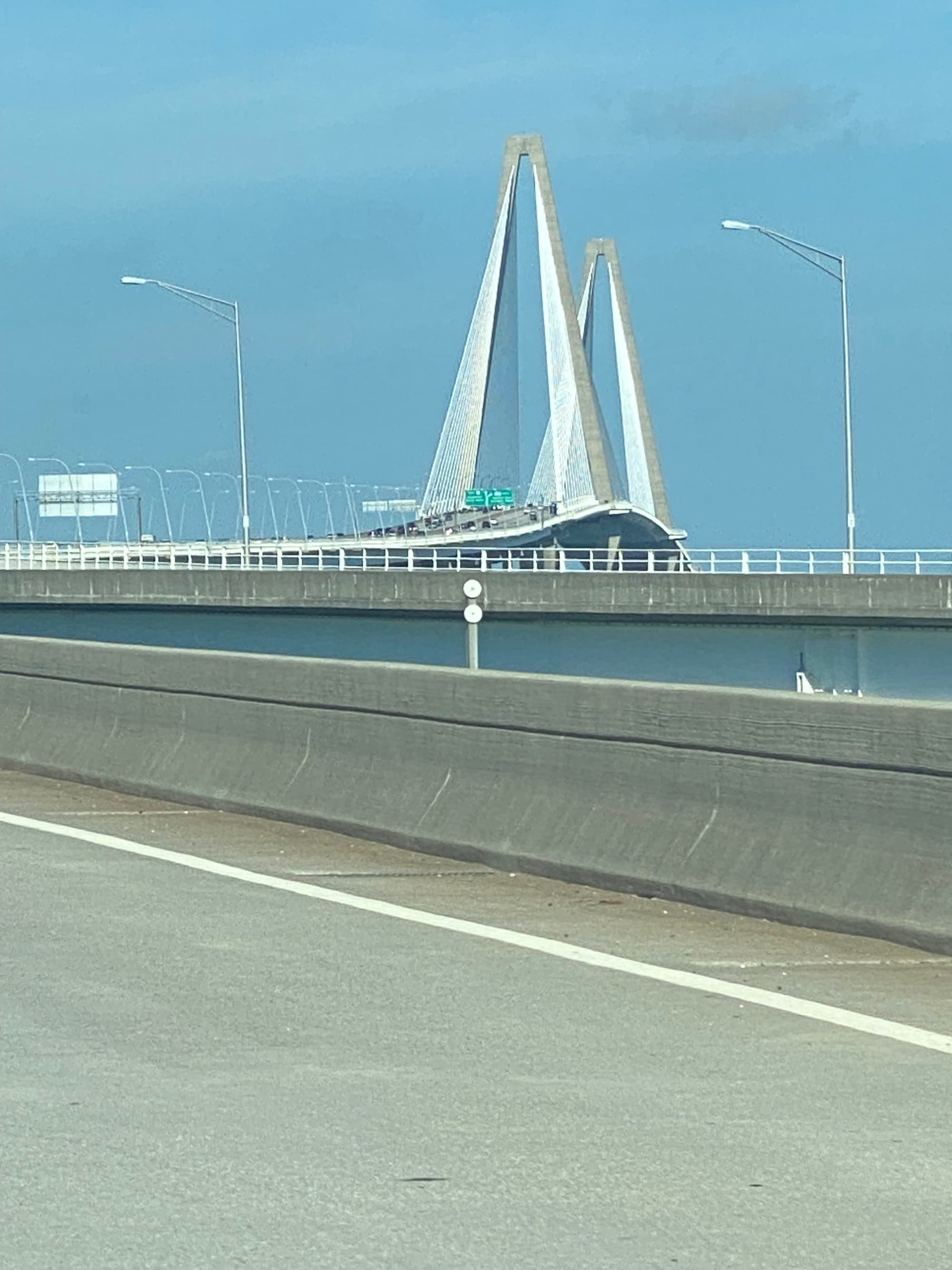 A suspension bridge with cables and towers under a clear blue sky.