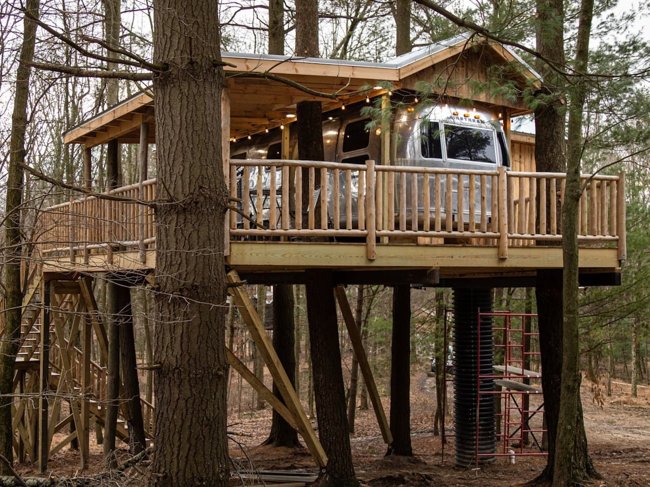 A treehouse in a forest with RV parked in it.
