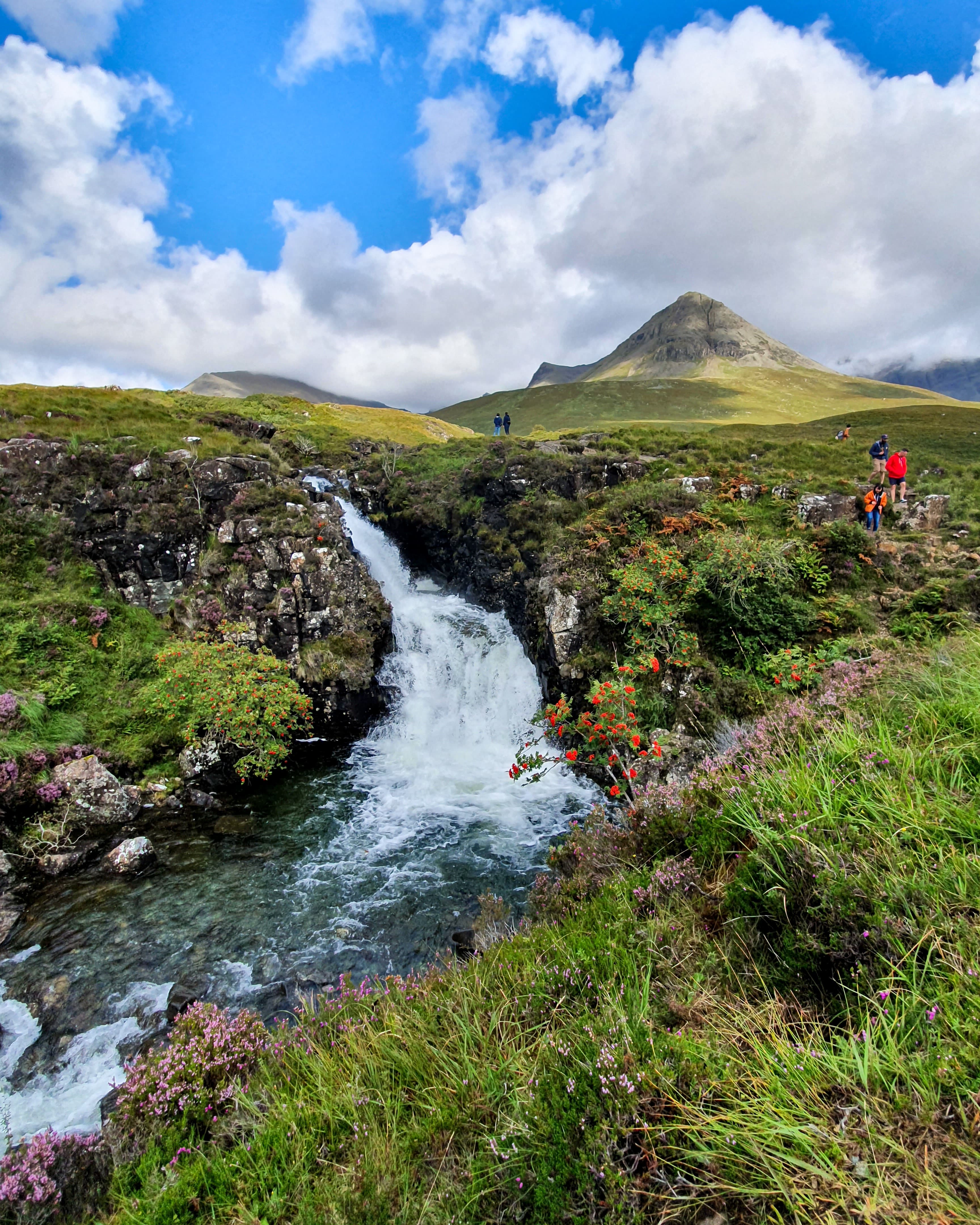 people walking near mountains and body of water