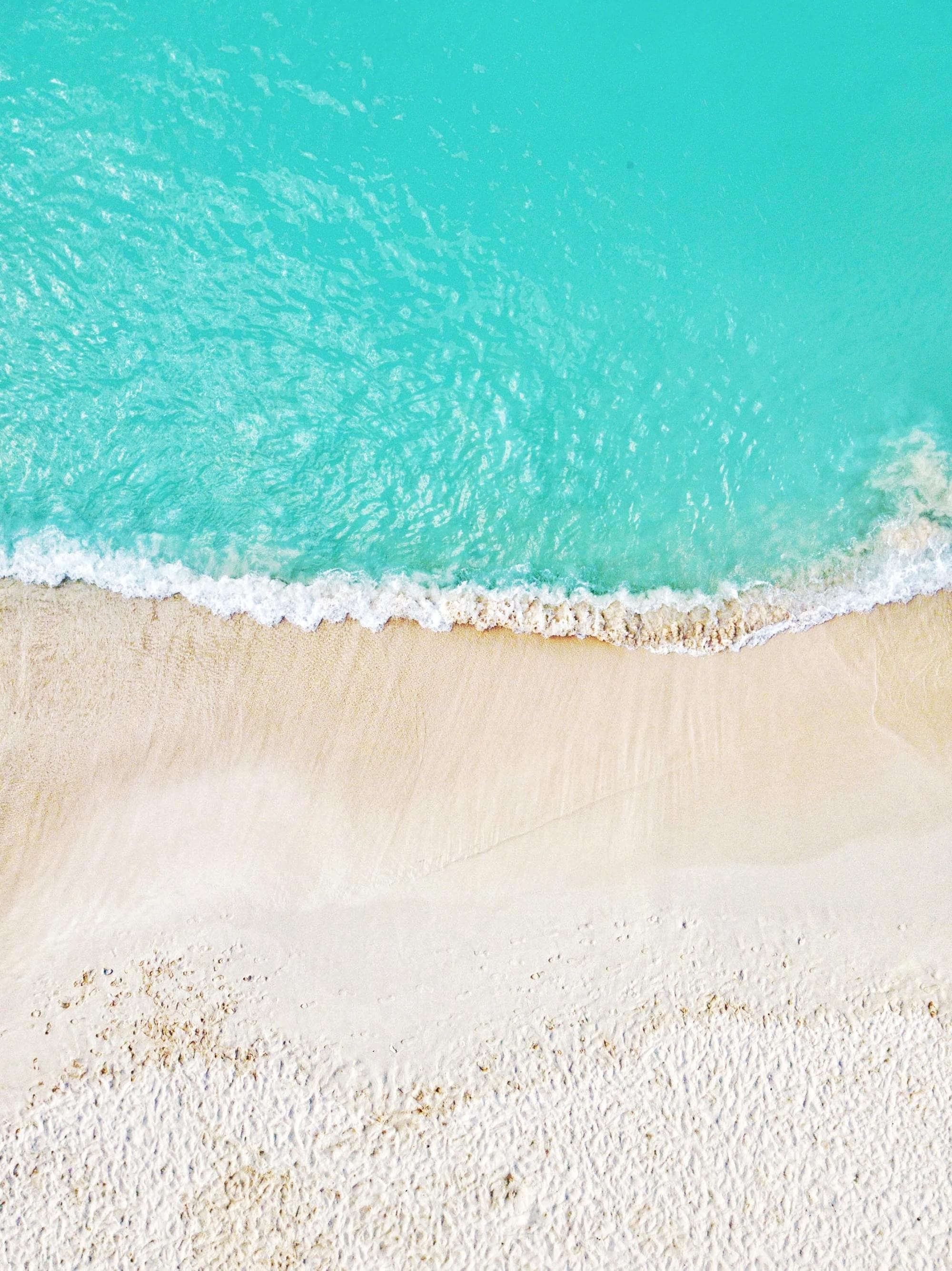aerial view of pristine blue water and white sand beach