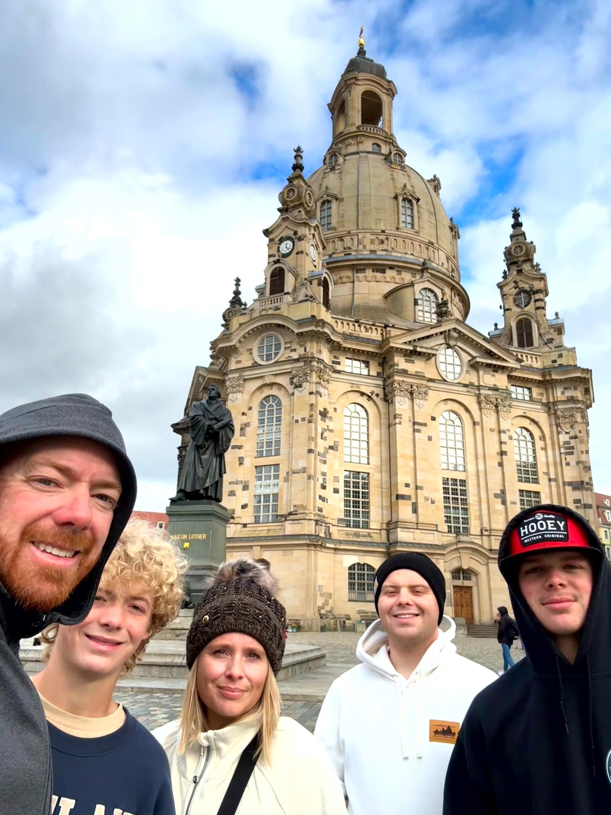 A family posing in front of architectural buildings during daytime.