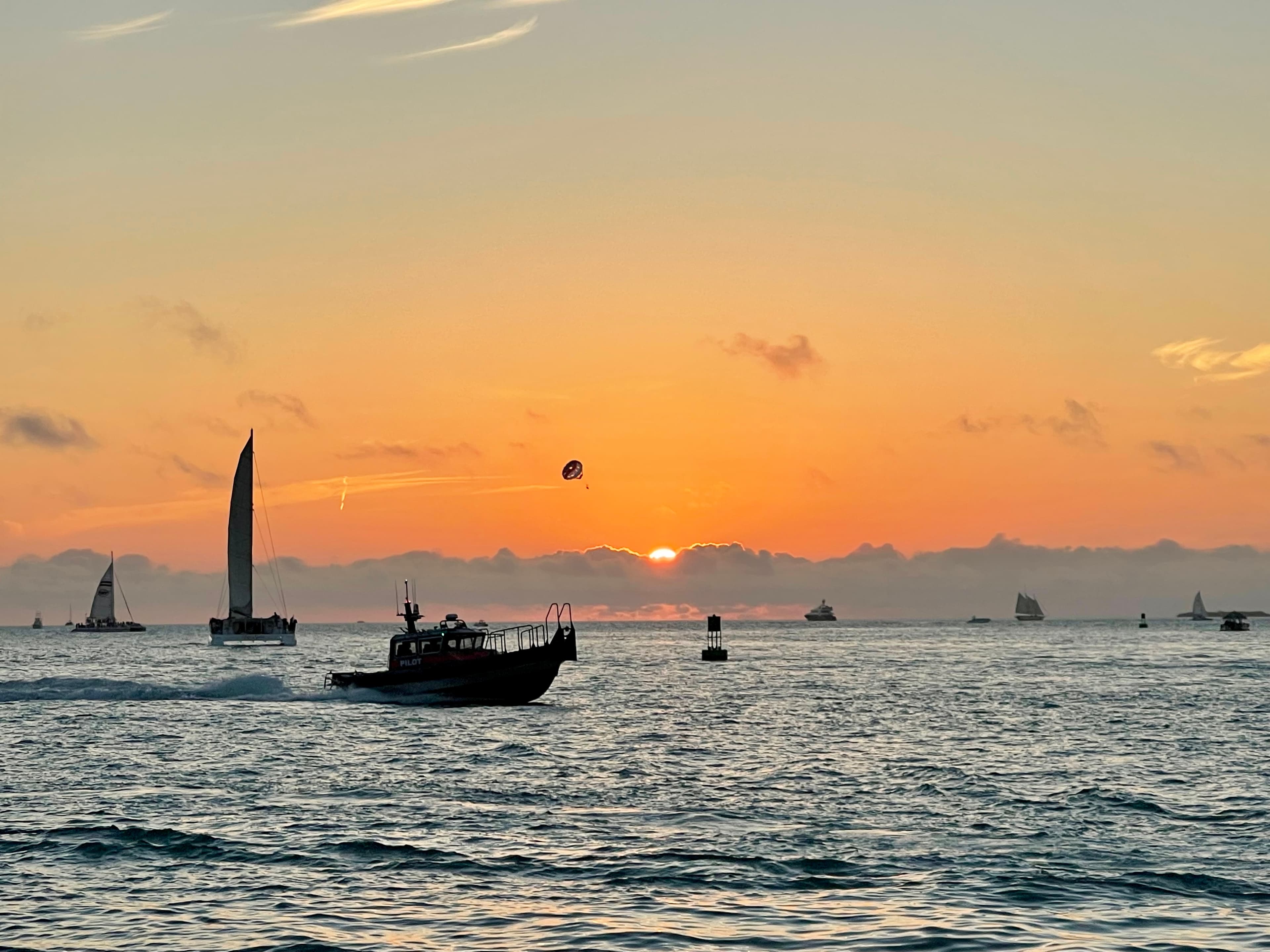 A sunset over the water with boats in the distance