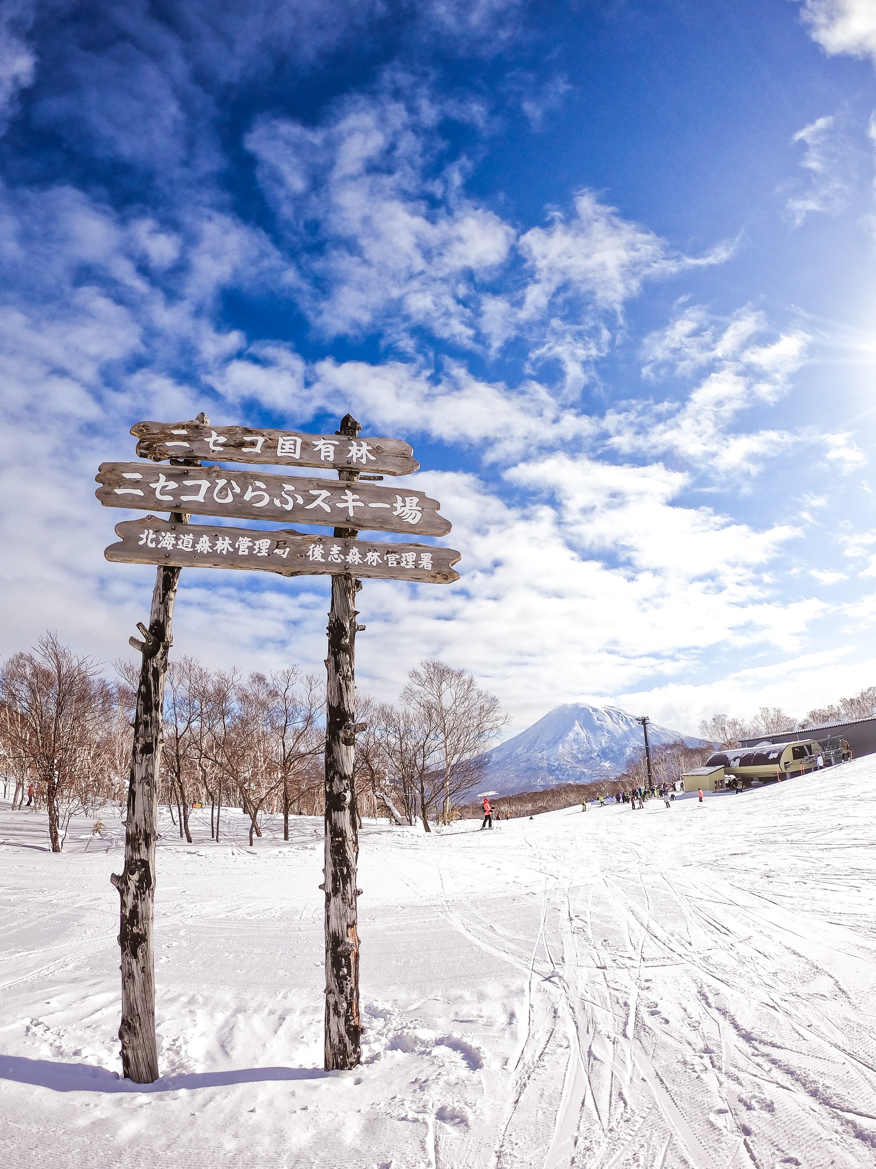 wood sign in the snow with mountain in the background during daytime