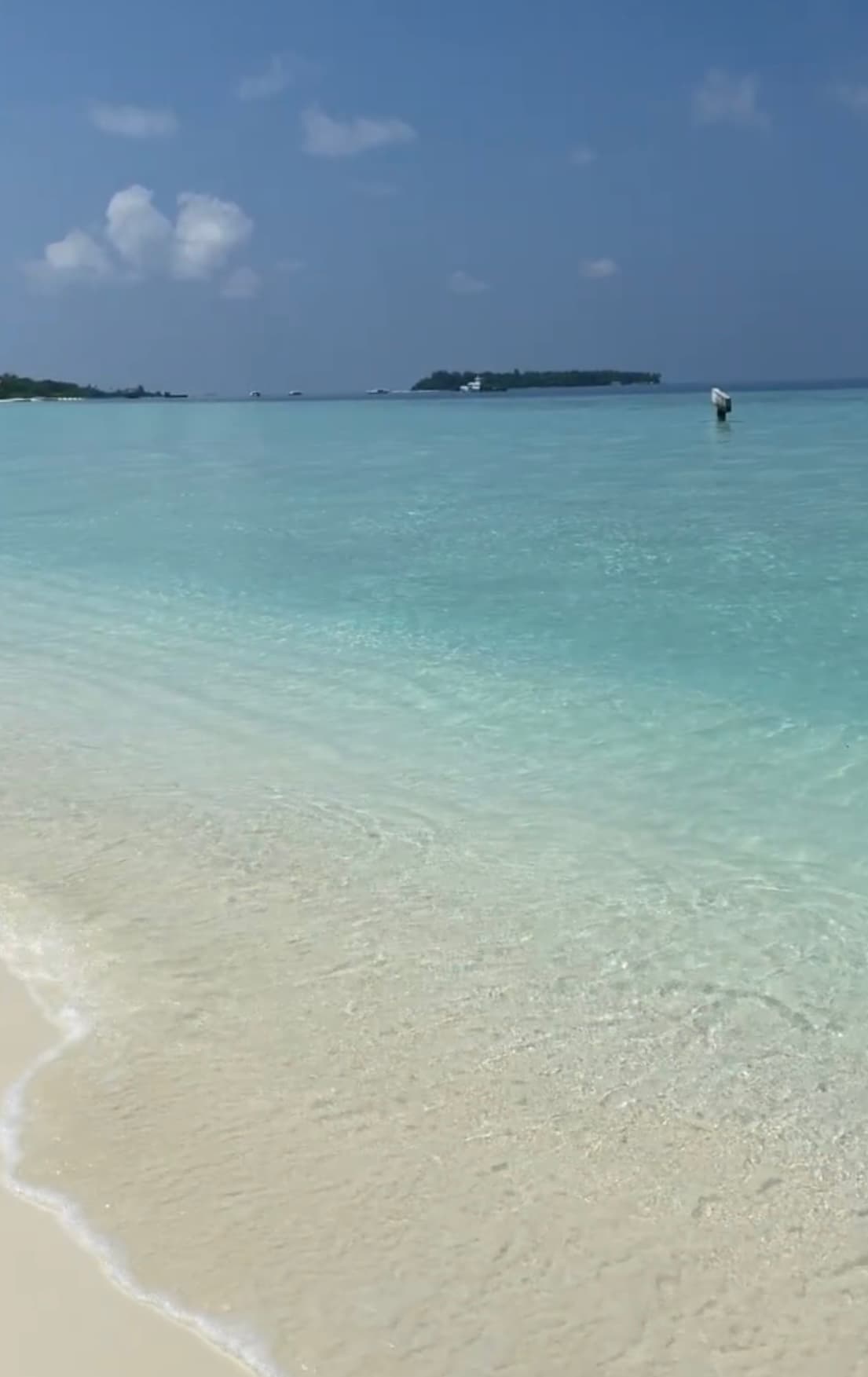A view of crystal clear blue water against the white sandy beach.