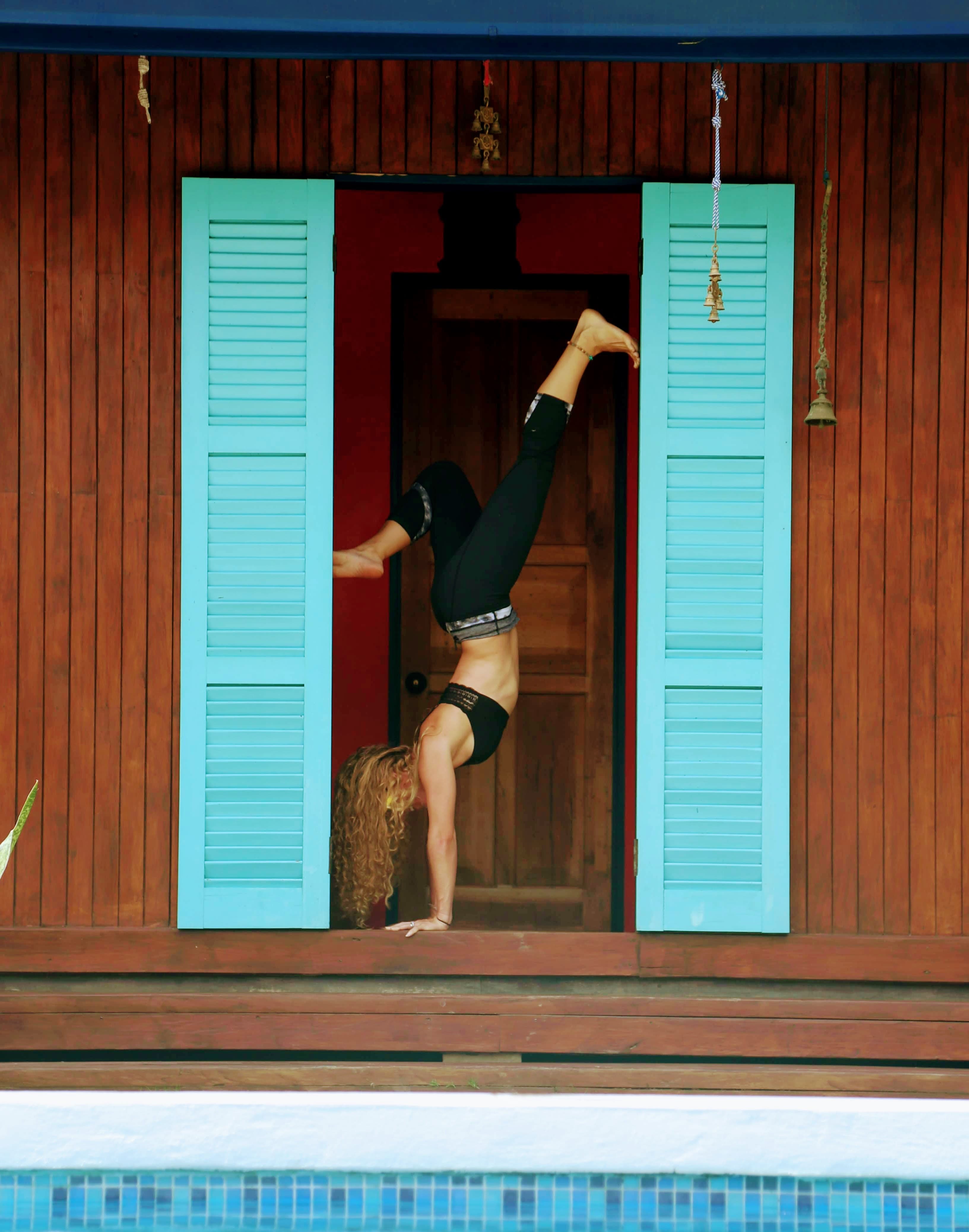 A yogi doing a headstand next to a blue door in Costa Rica.