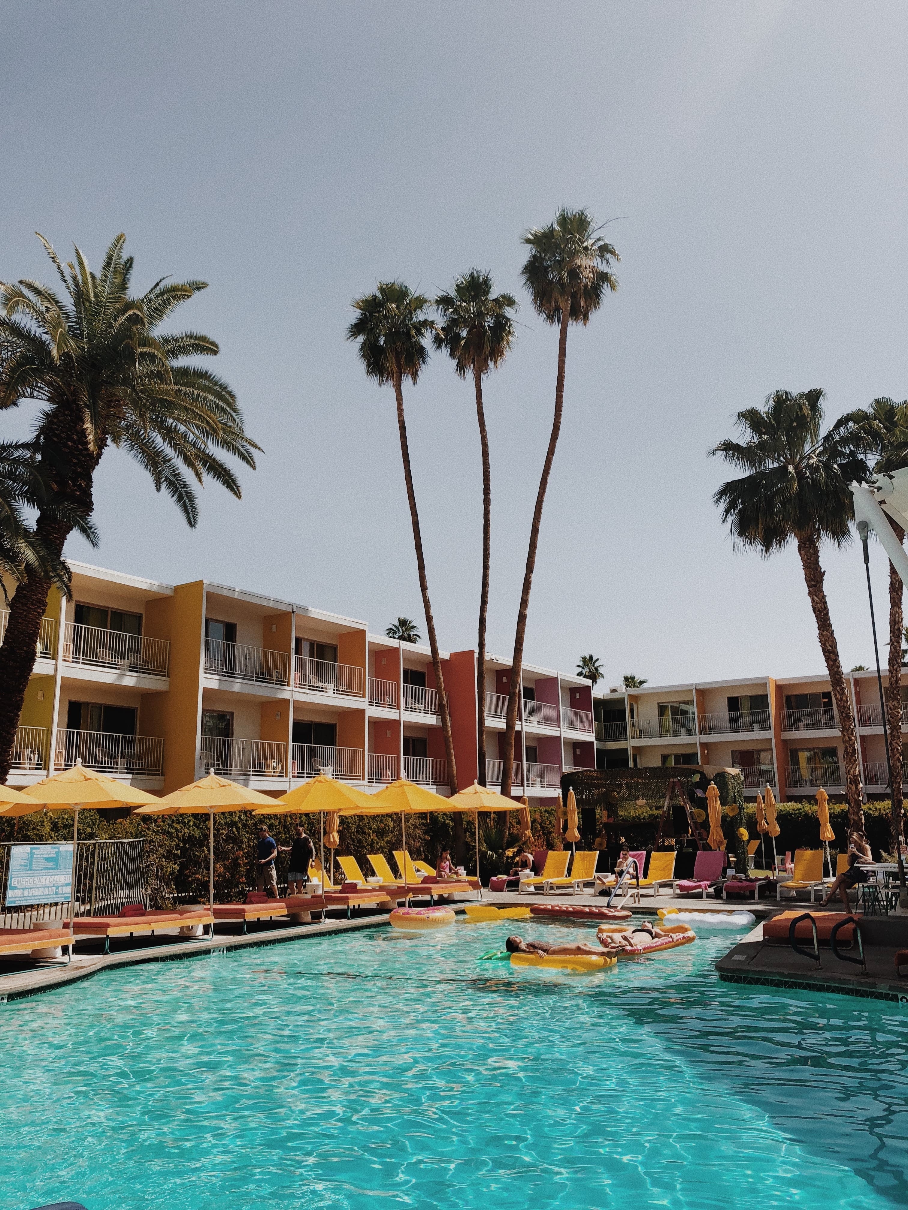 A hotel pool surrounded by yellow umbrellas in Palm Springs.
