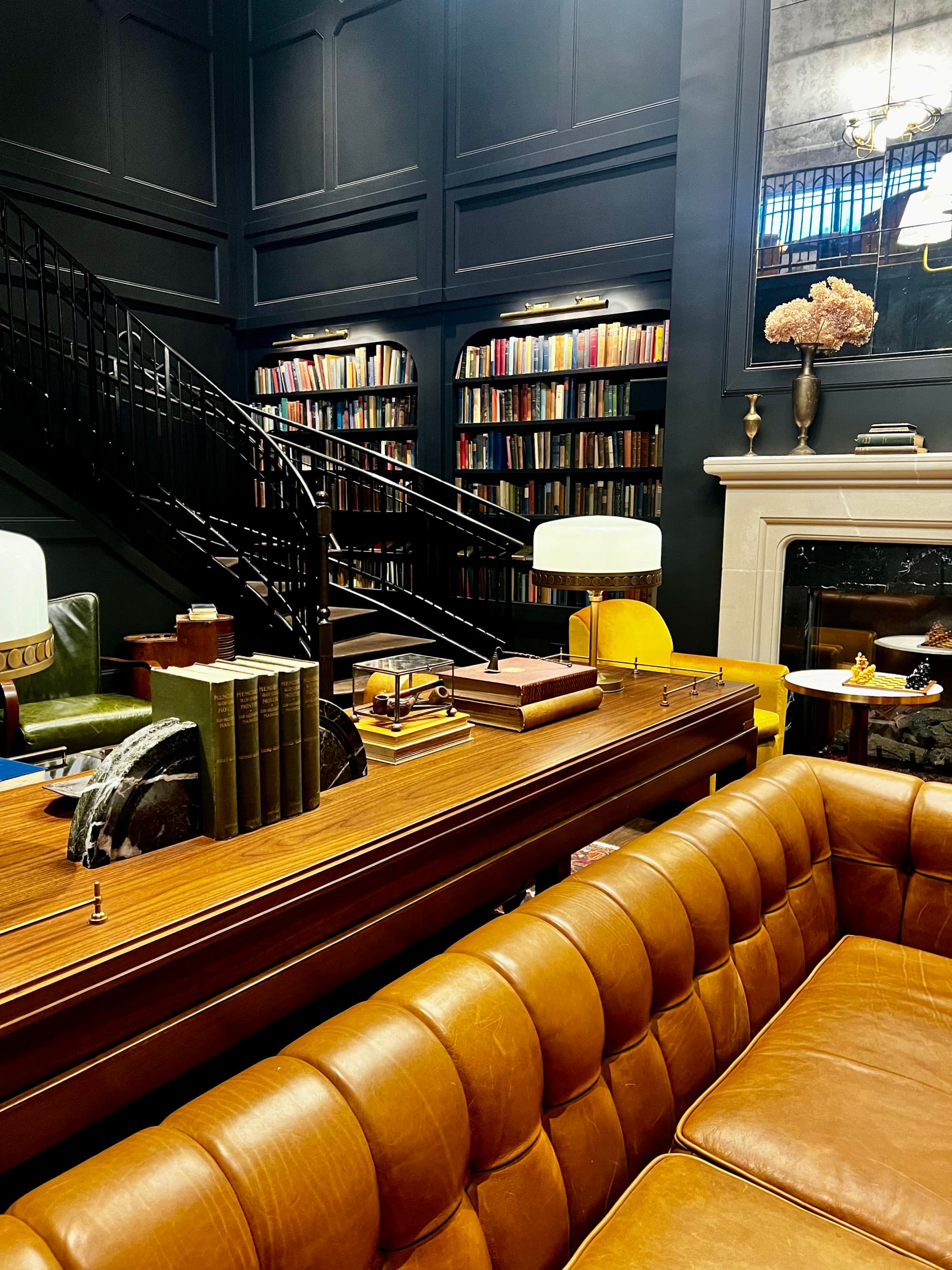 A sitting area with black walls, bookshelves, a white fireplace and a brown leather booth.