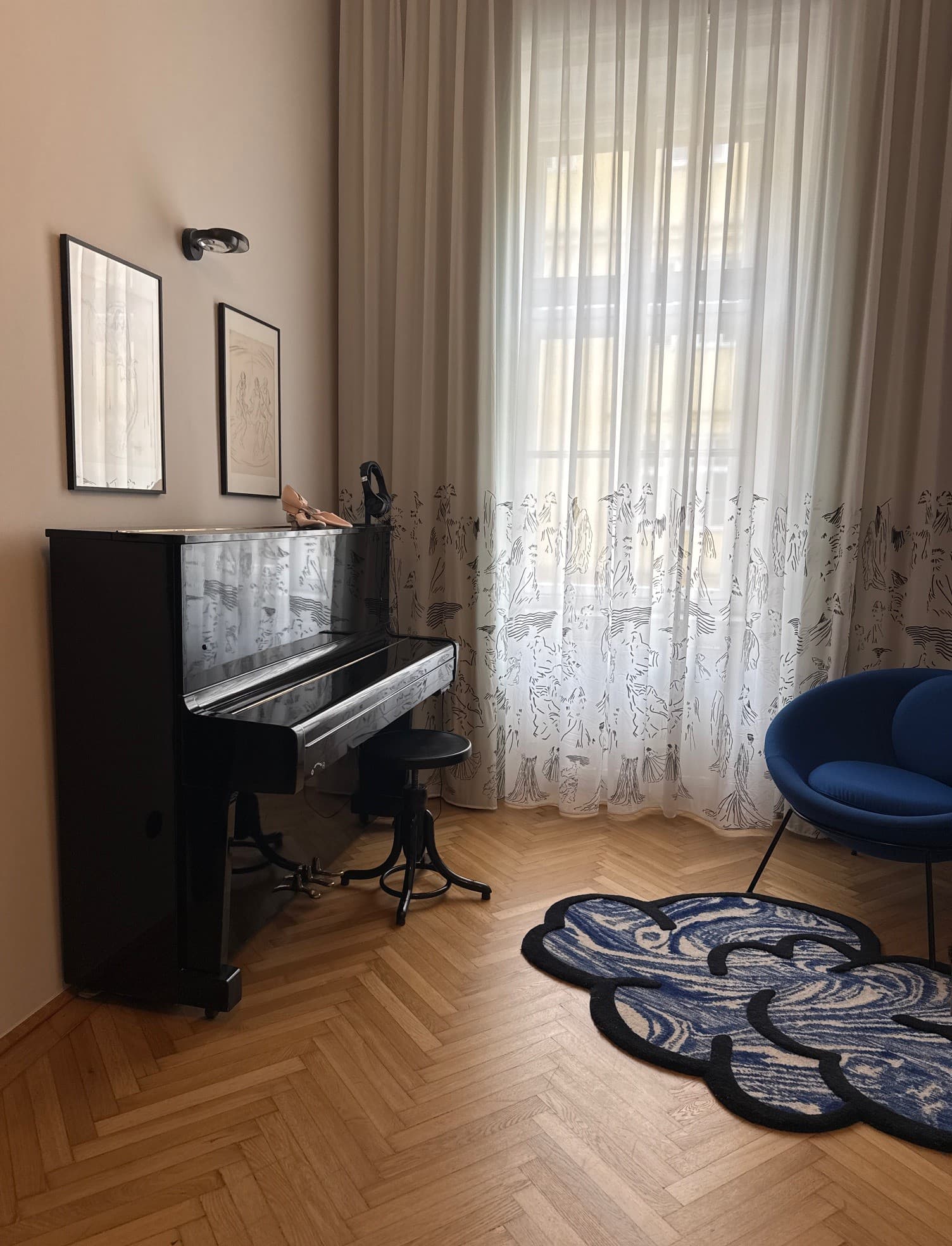 A hotel room suite with a black, wooden piano in front of a tall window