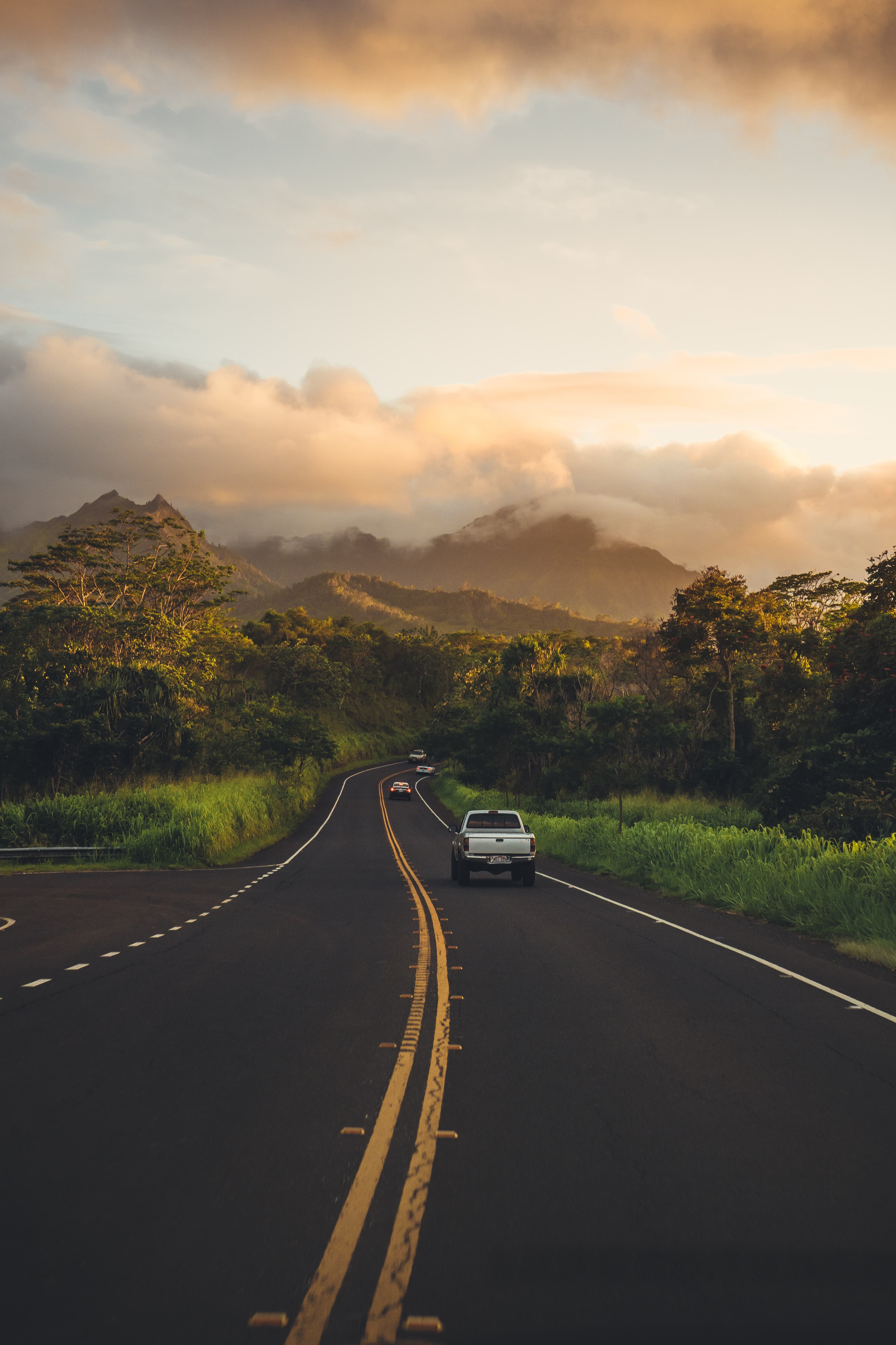 A highway in Hawaii framed by mountains and clouds.