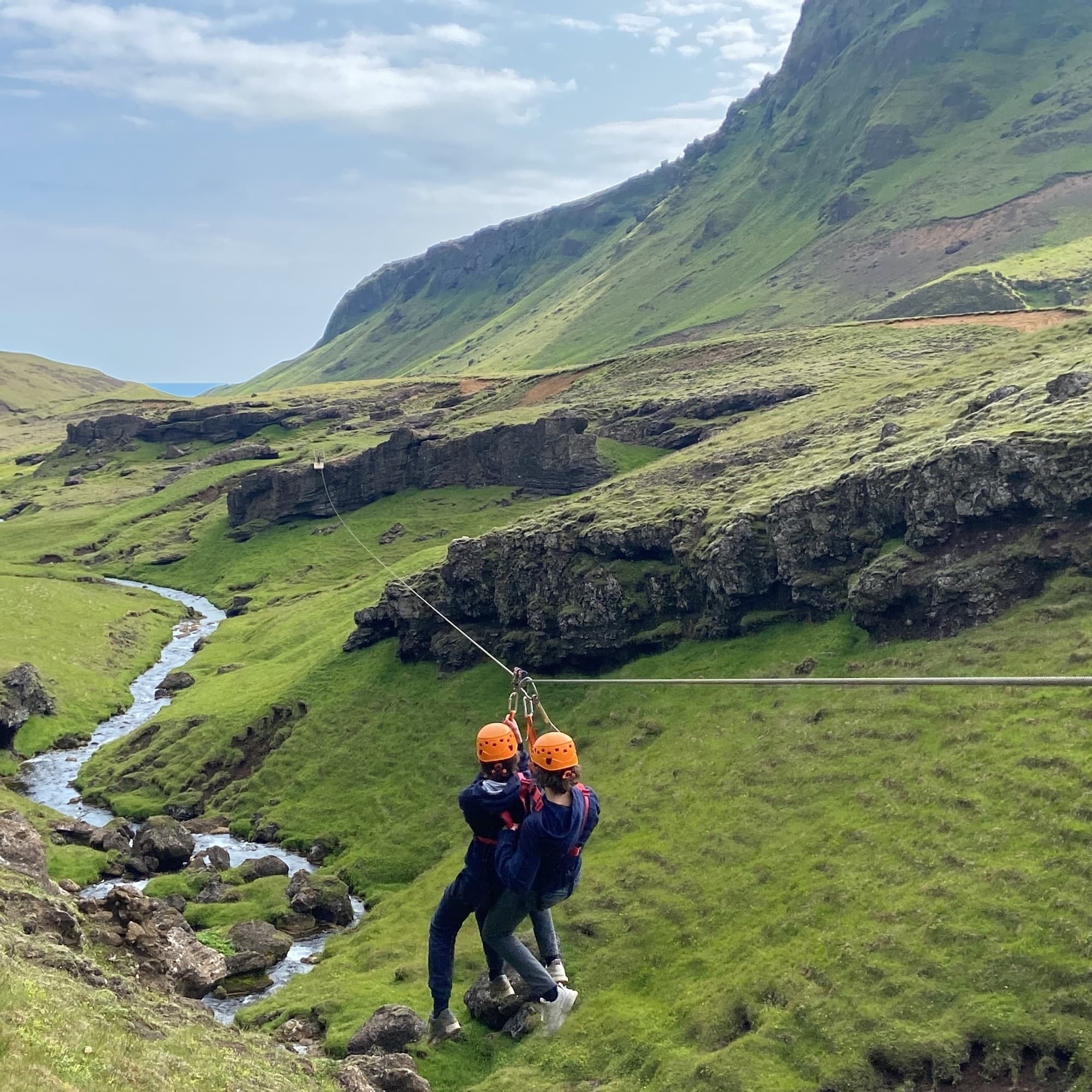 Two thrill-seekers zip-lining over a verdant valley, embracing adventure in the great outdoors.