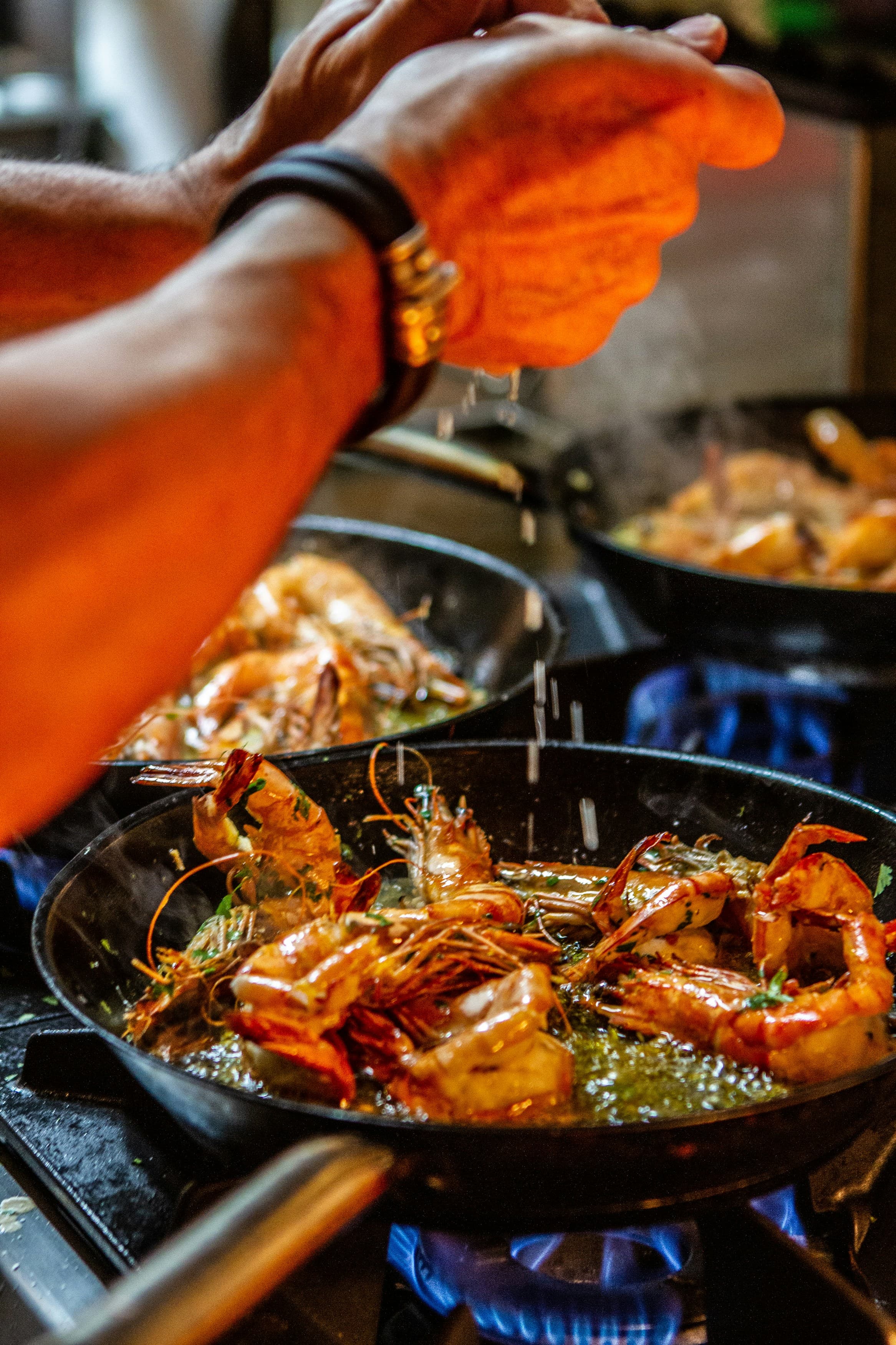 A picture of a chef squeezing an ingredient onto a seafood dish on the stove