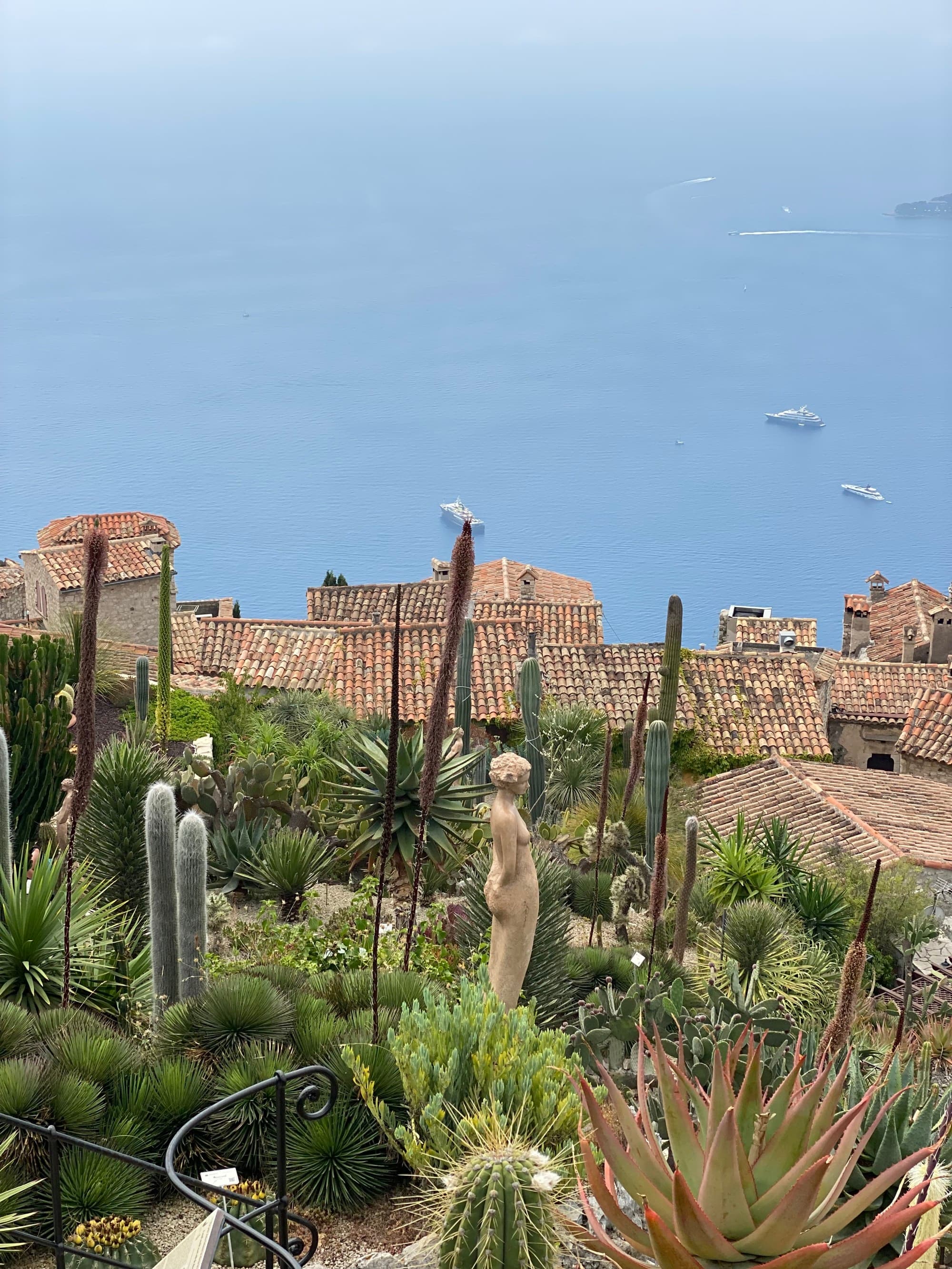 A view of a hillside with a garden and quaint overlooking the ocean.