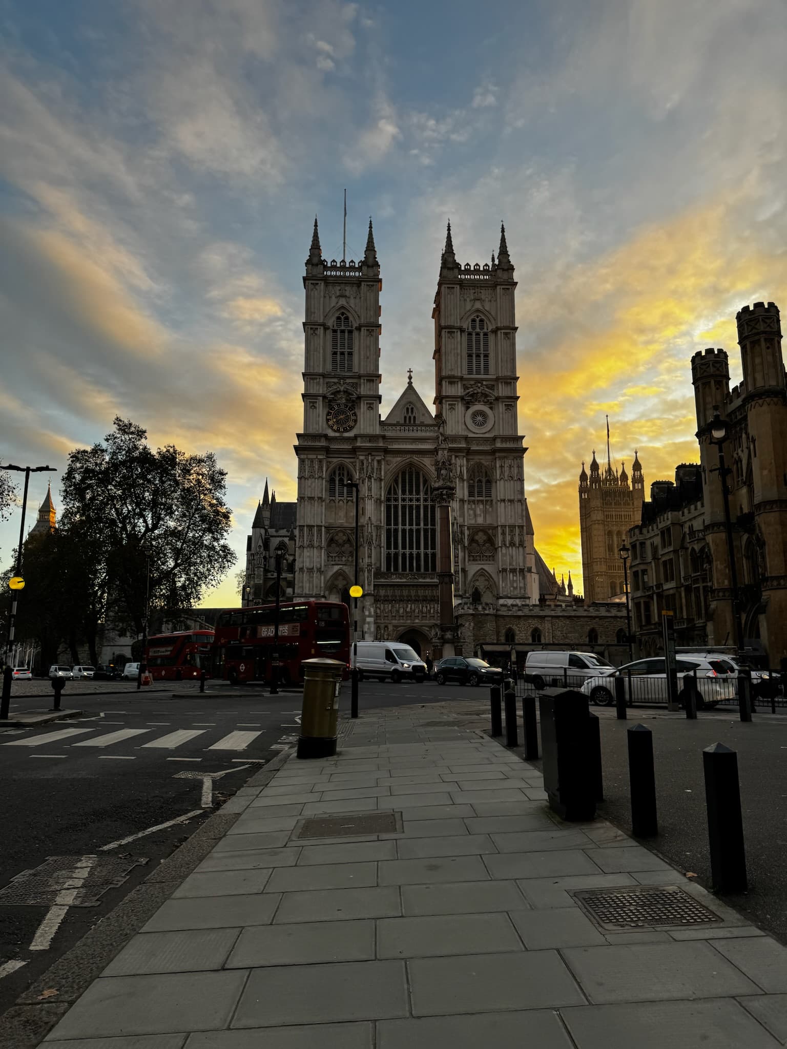 A London street displaying a prominent, stone, church building against a multi-colored sky.