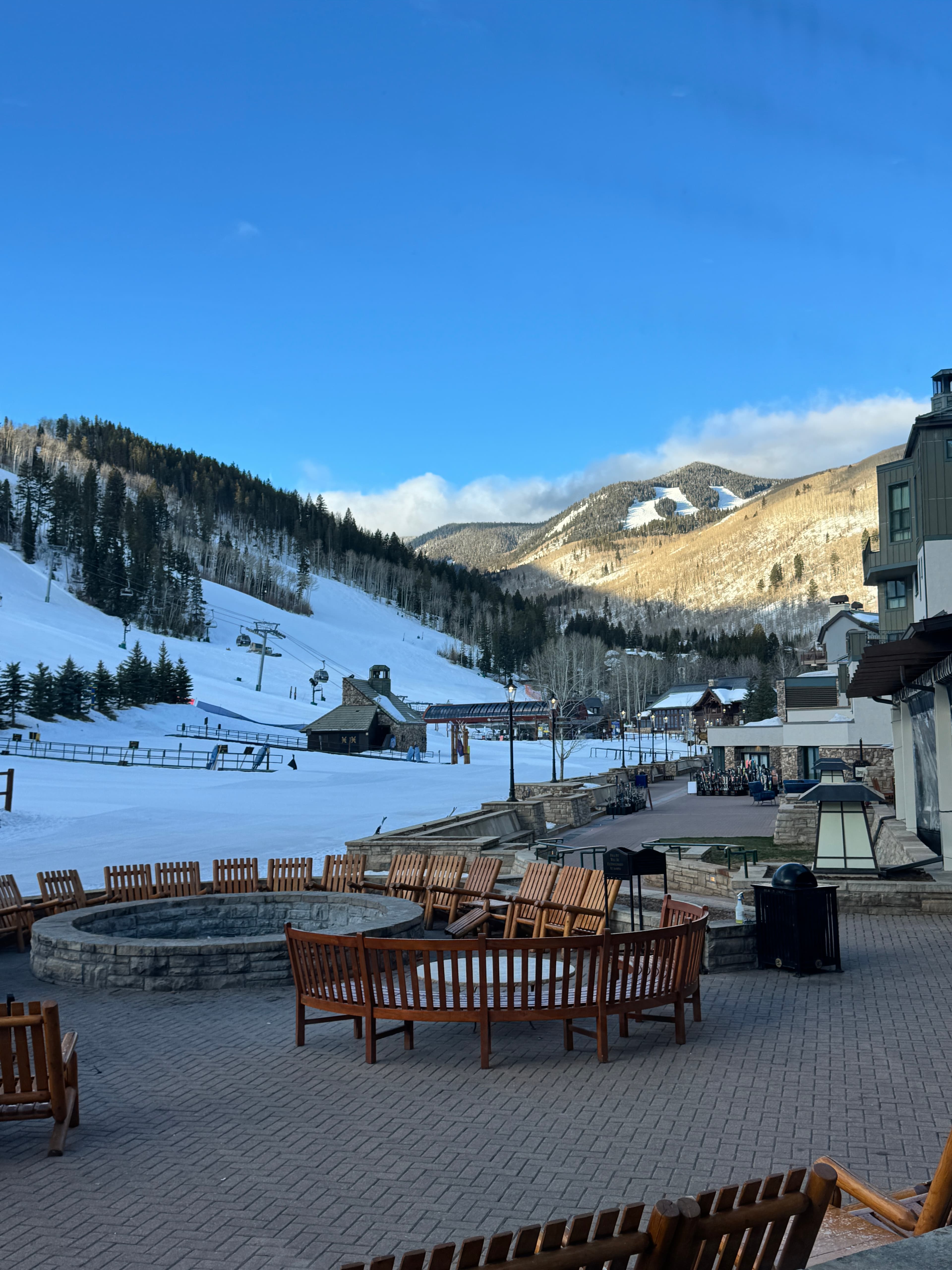 A view outside of a Colorado ski resort during the daytime, showing the venue's grand patio and snow-covered mountains.