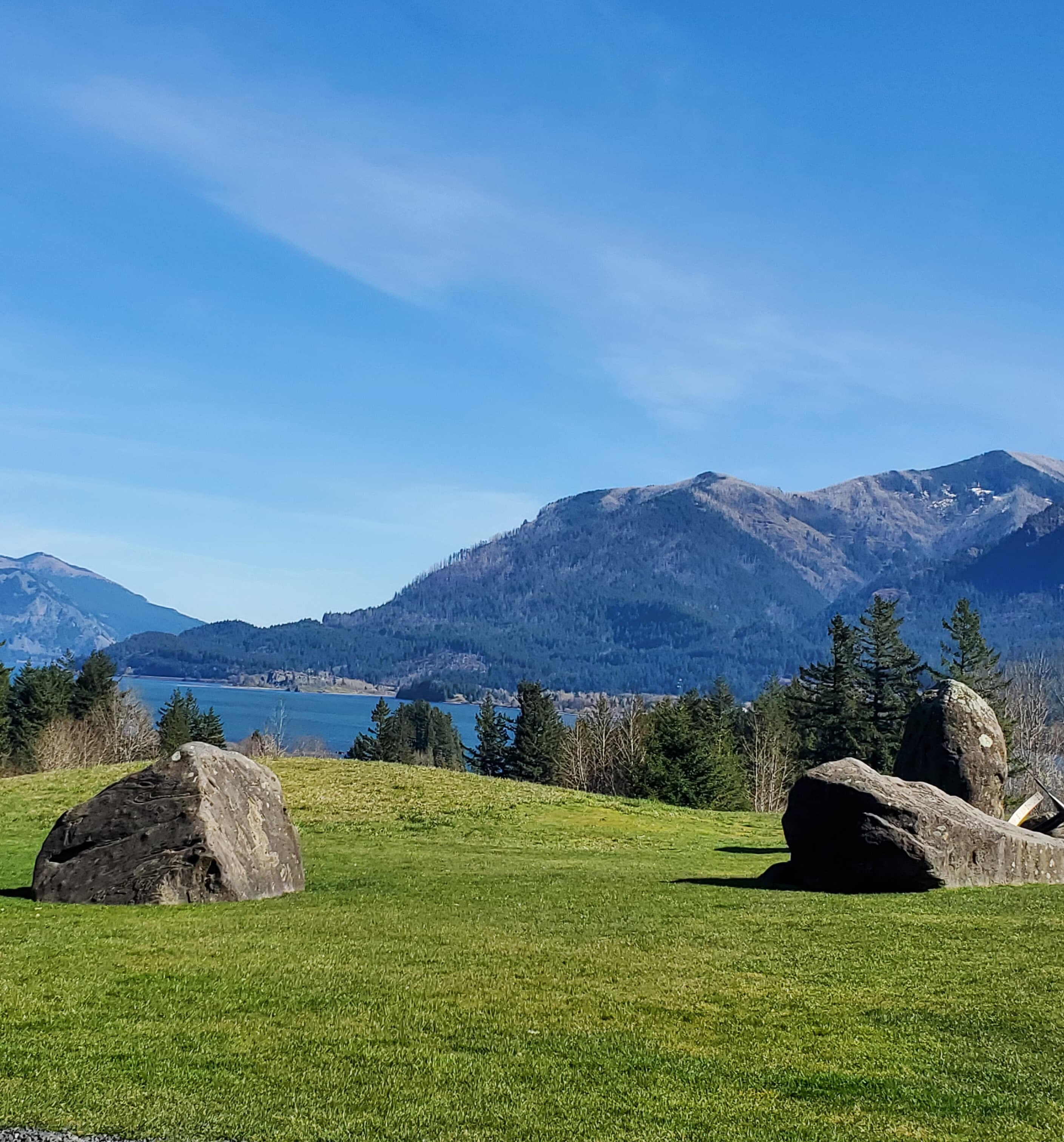 A photo of boulders, a lake and the Columbia River Gorge in the background.
