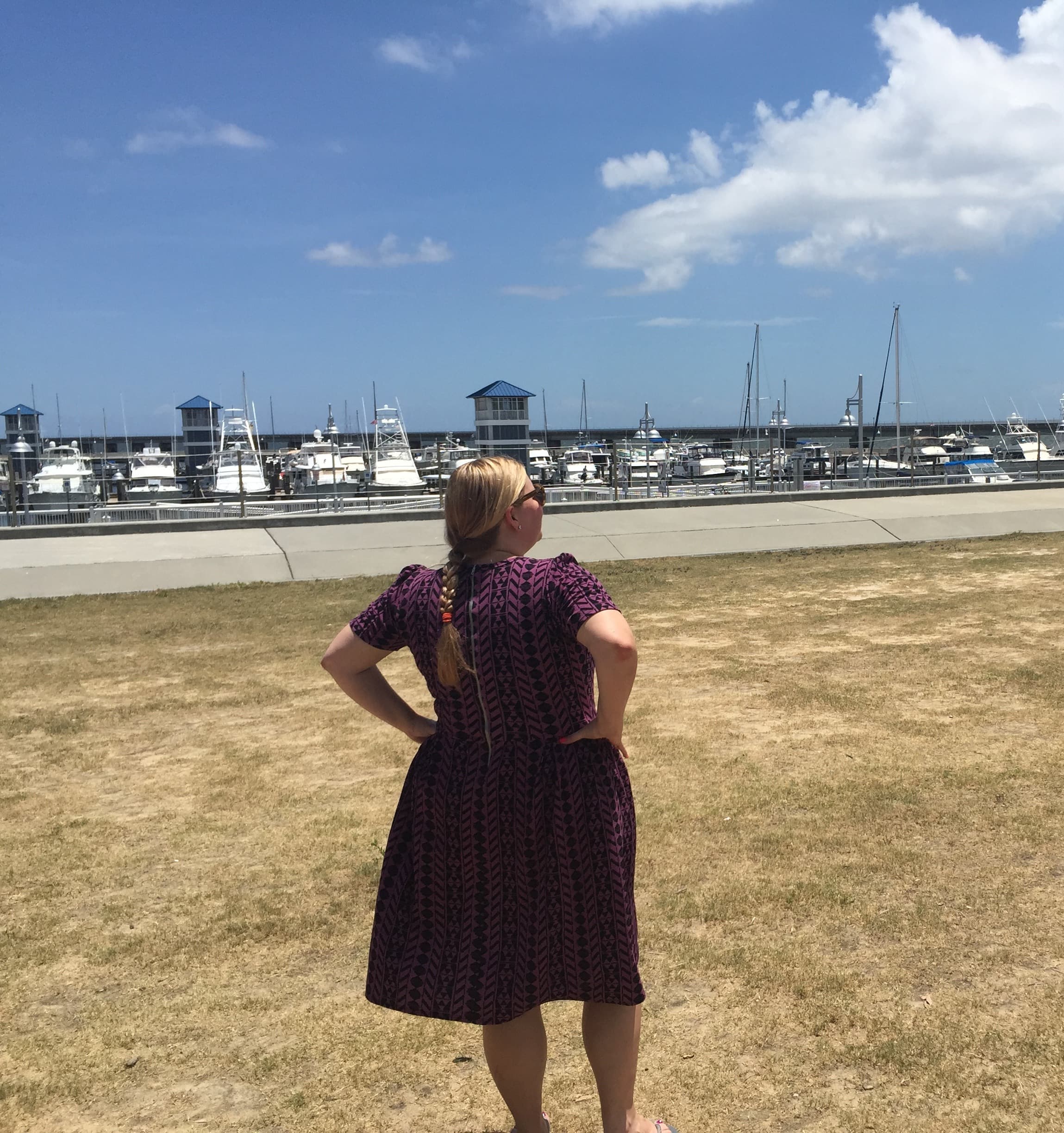 Gillian looking into the distance of the bay with a boat dock.