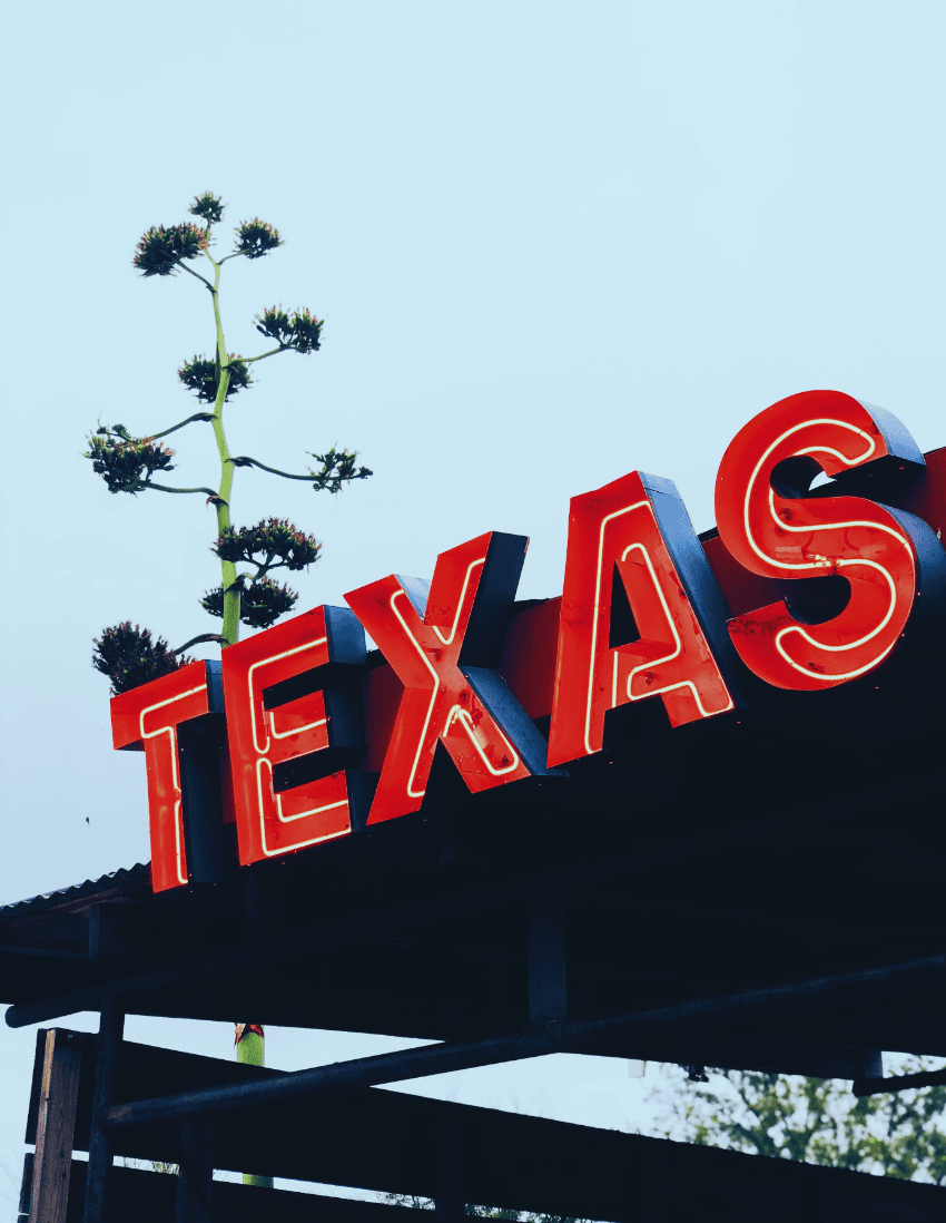 A red neon sign that reads "Texas" on the exterior of a building outside.
