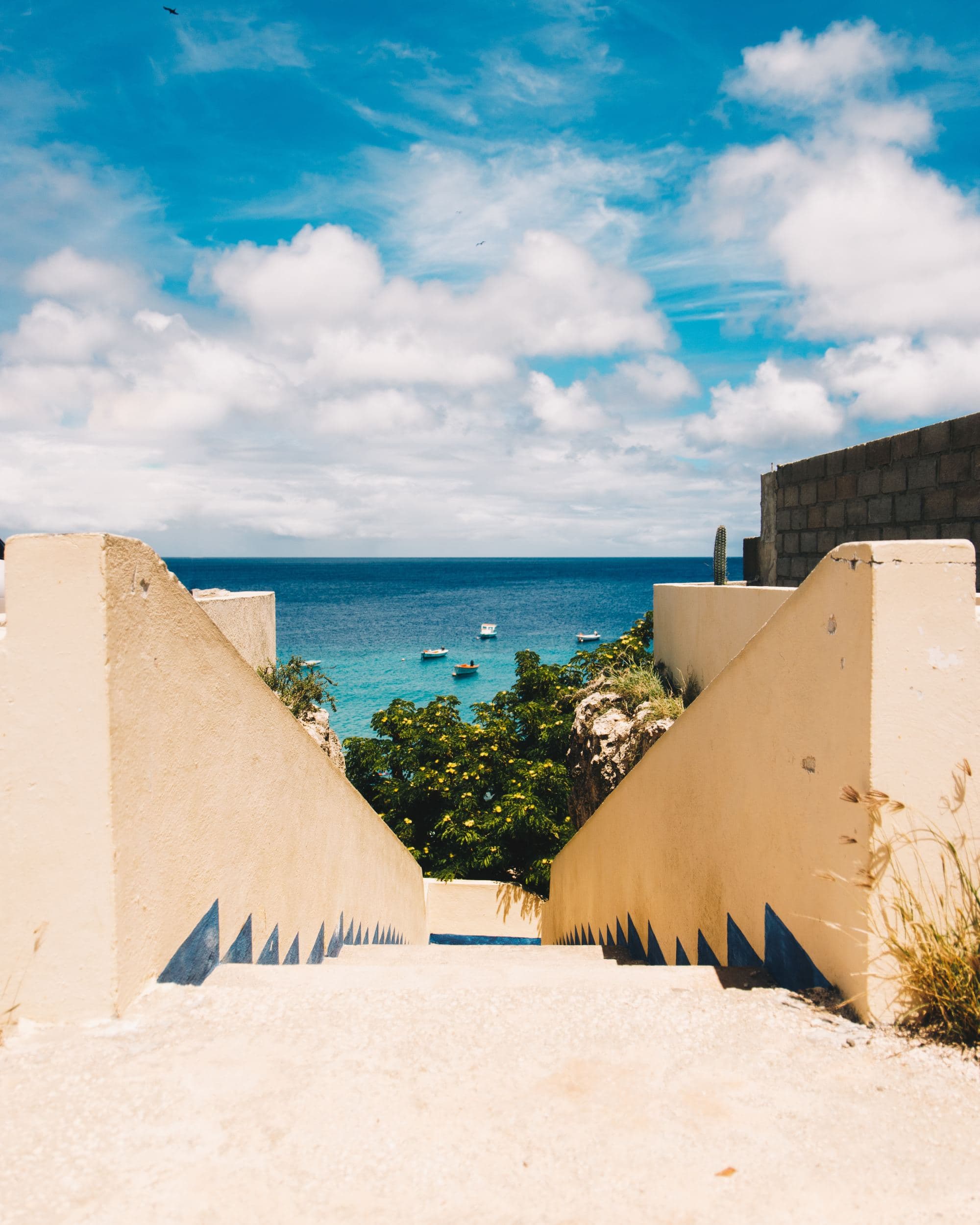 stairs down to a tropical beach with boats on a sunny day