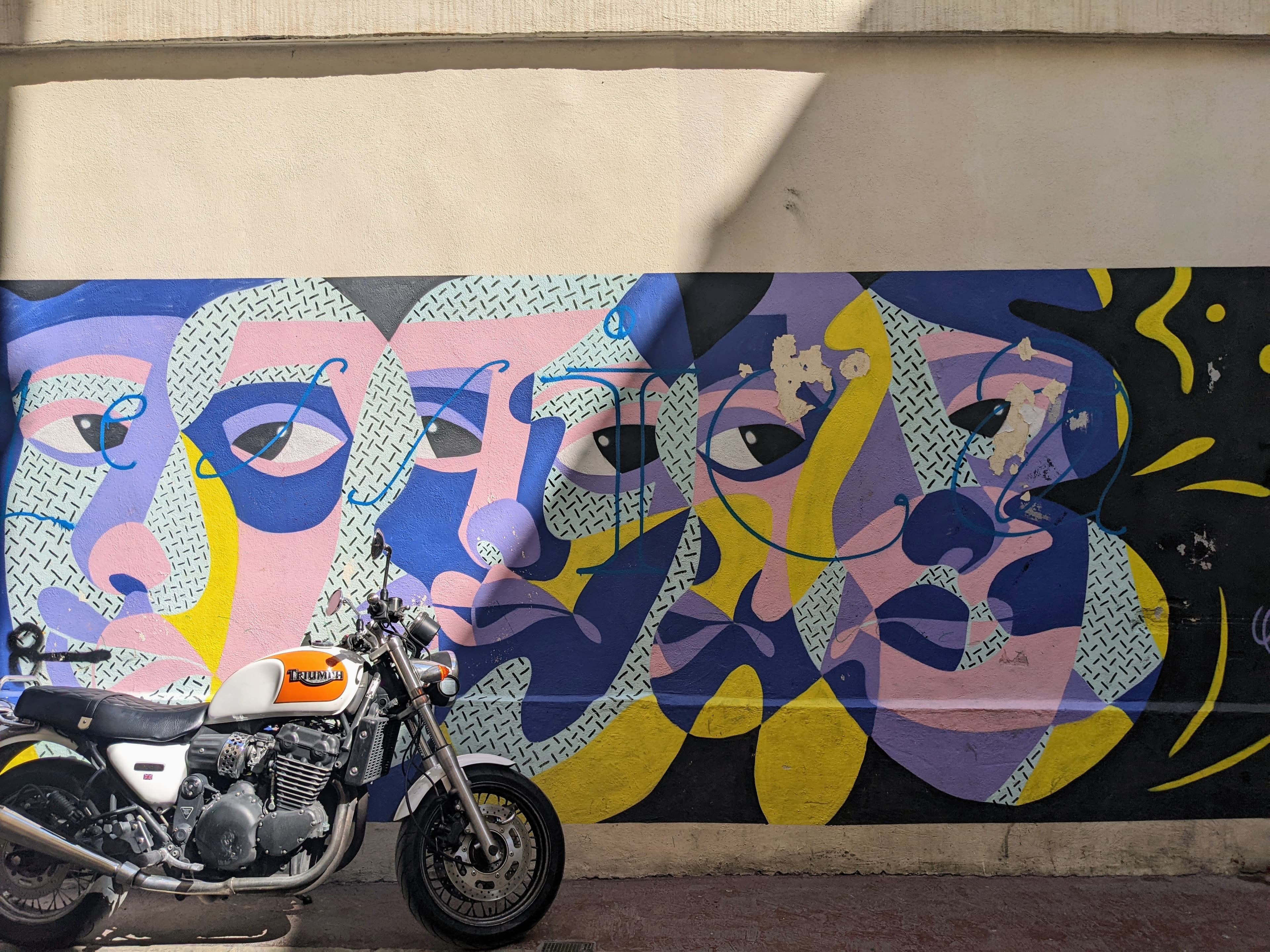 A motorcycle next to street art in Marseille.